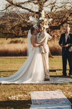 Outdoor wedding ceremony setup with white aisle runner and autumn foliage in the background.