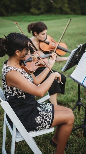 String musicians in black and white attire performing at an outdoor wedding.