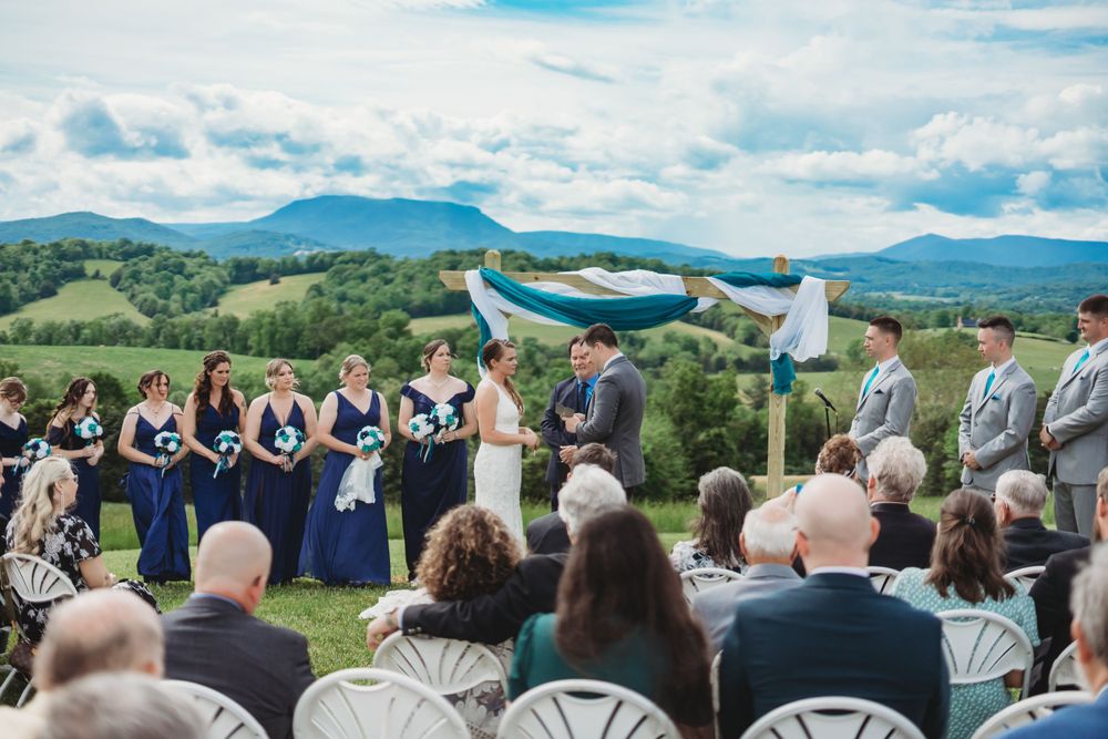 Panoramic view of wedding guests seated facing mountains under blue skies.