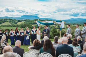 Panoramic view of wedding guests seated facing mountains under blue skies.