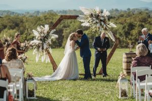 Wide angle view of outdoor wedding ceremony setup with white chairs and mountain backdrop.