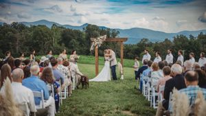 Wedding guests gathered on a hillside with blue mountain vistas in the background.