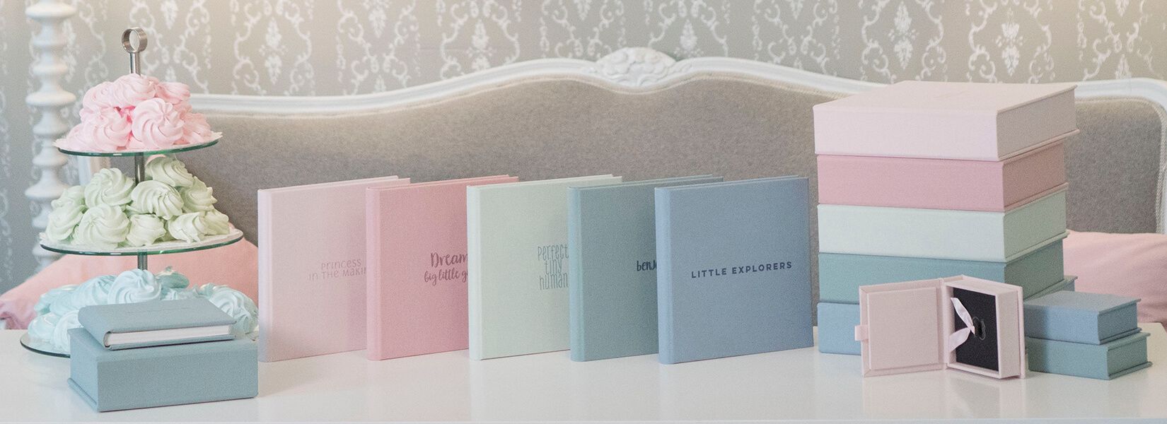 Elegant pastel pink and blue photo albums and boxes arranged in a soft, minimalist display.