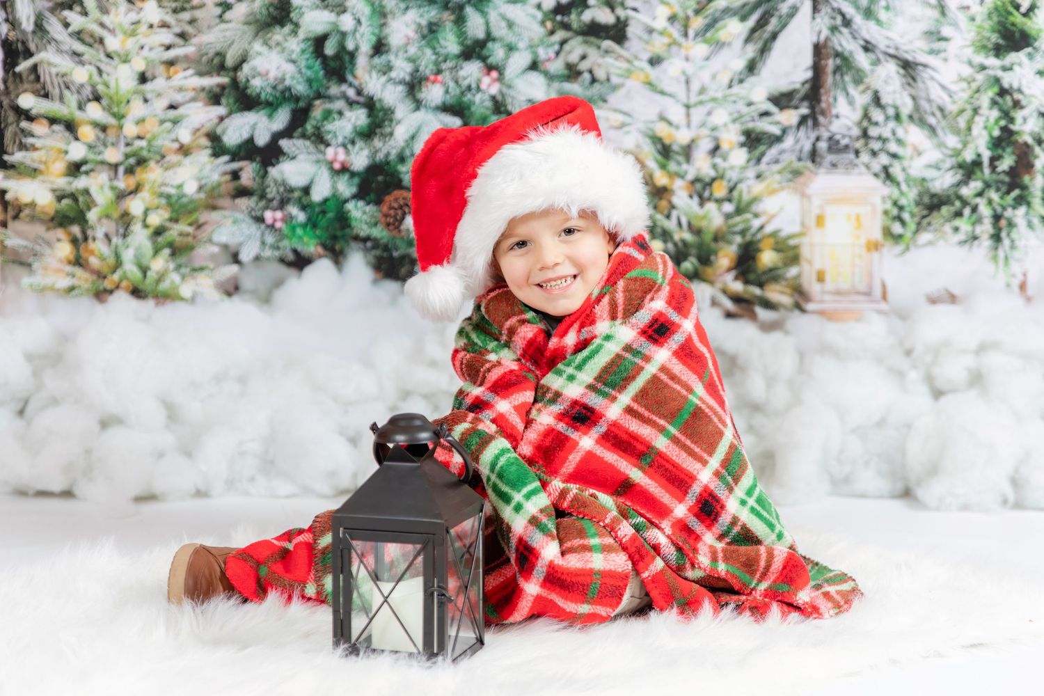 child wrapped in christmas blanket wearing santa hat with tree backdrop and snow in studio clayton new jersey Gloucester