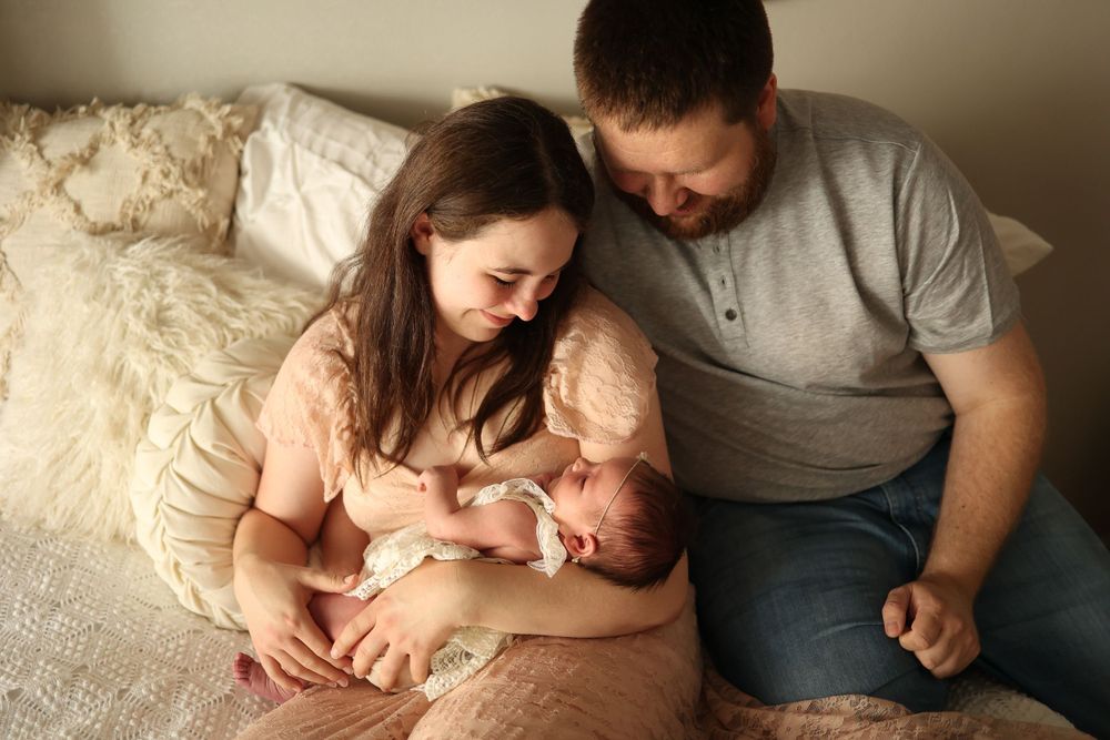 Tender moment of new parents with baby on cozy bed.
