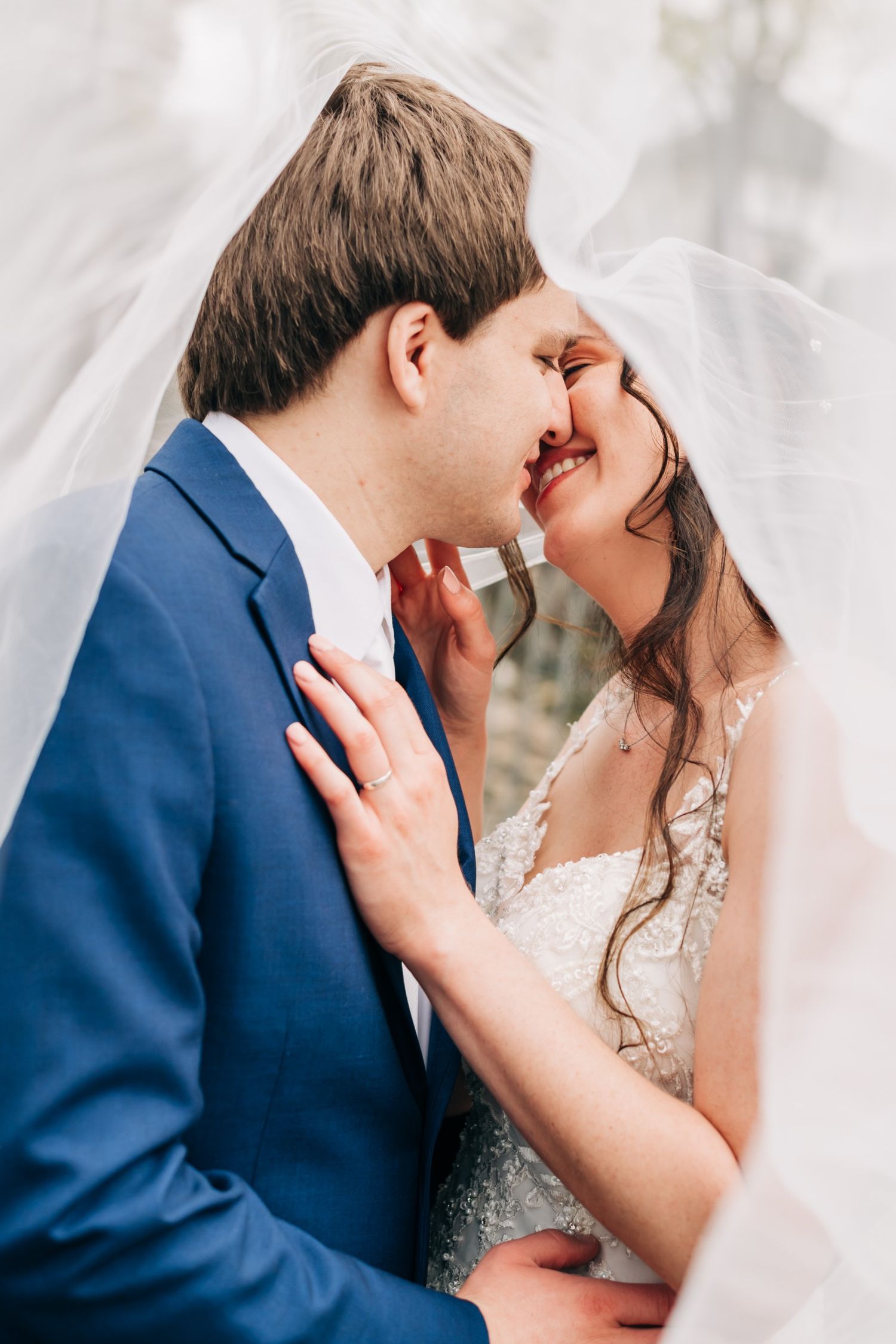 bride and groom snuggle under bride's veil