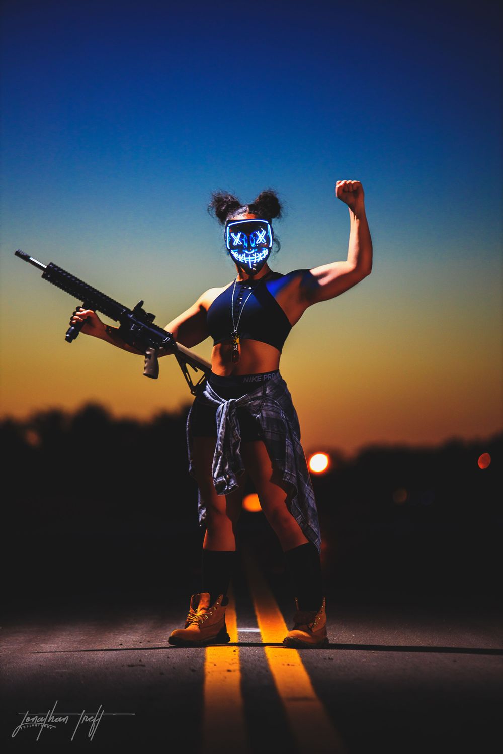 Sara in light mask holding M4 with one fist to the sky