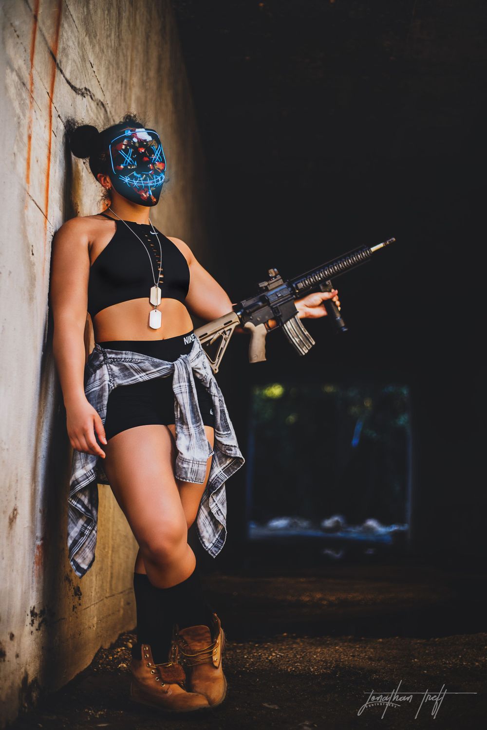 Sara leaning on wall wearing light mask holding M4