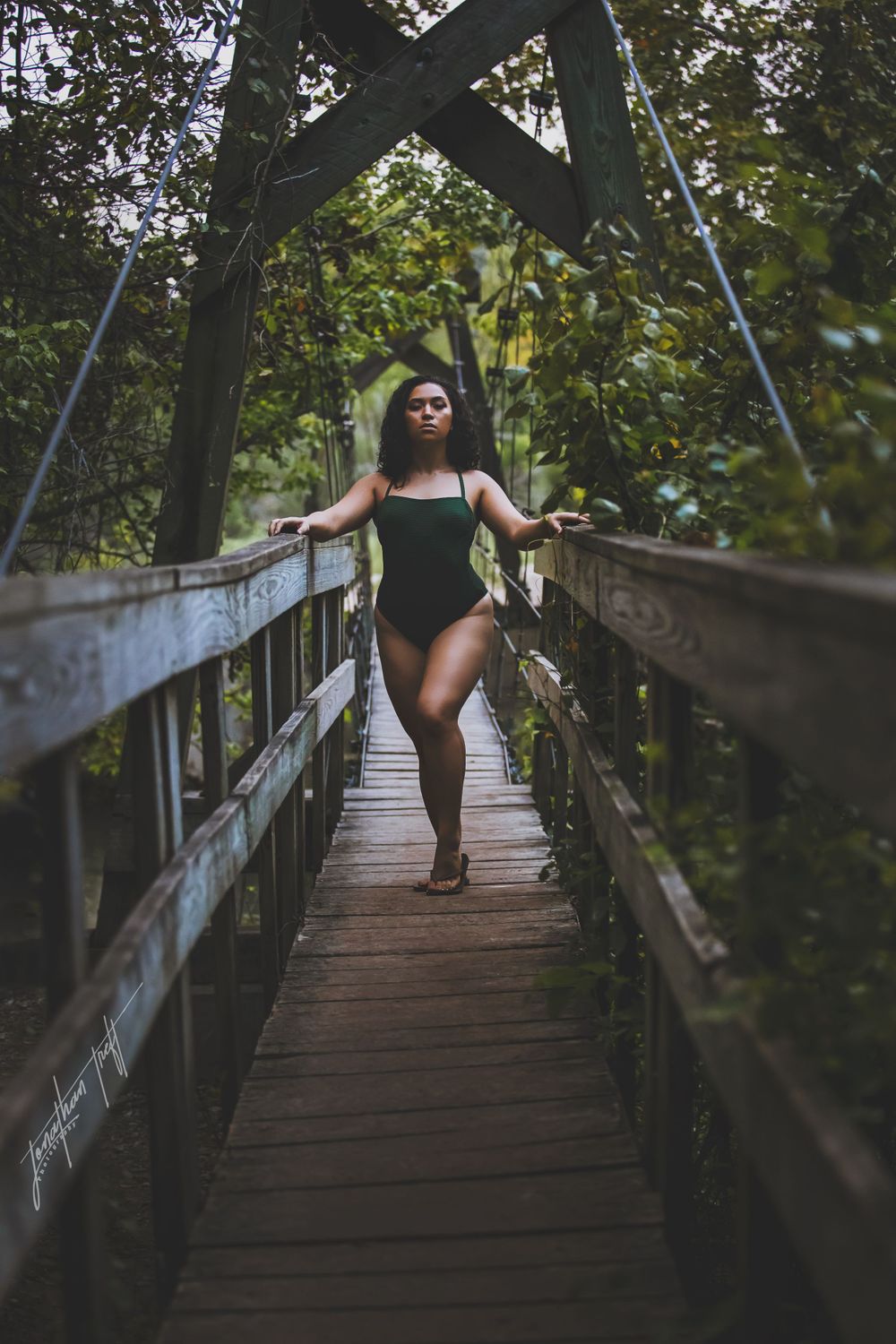 Sara in swimsuit standing on wooden suspended bridge