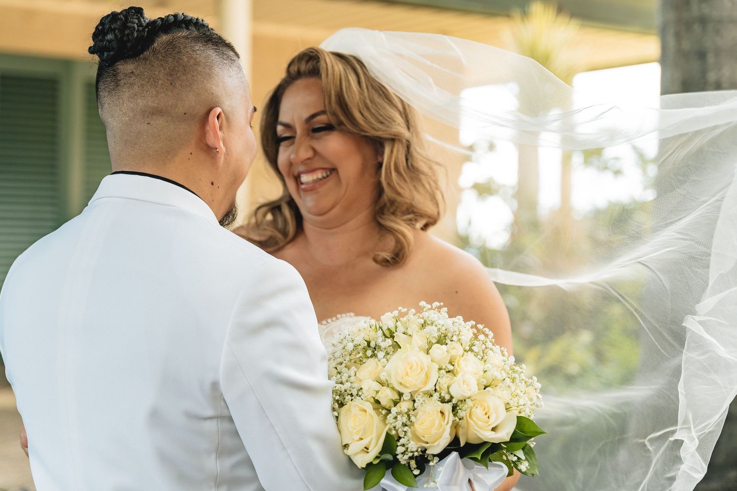 A joyful wedding moment with a beautiful bouquet of white roses shared between a couple.