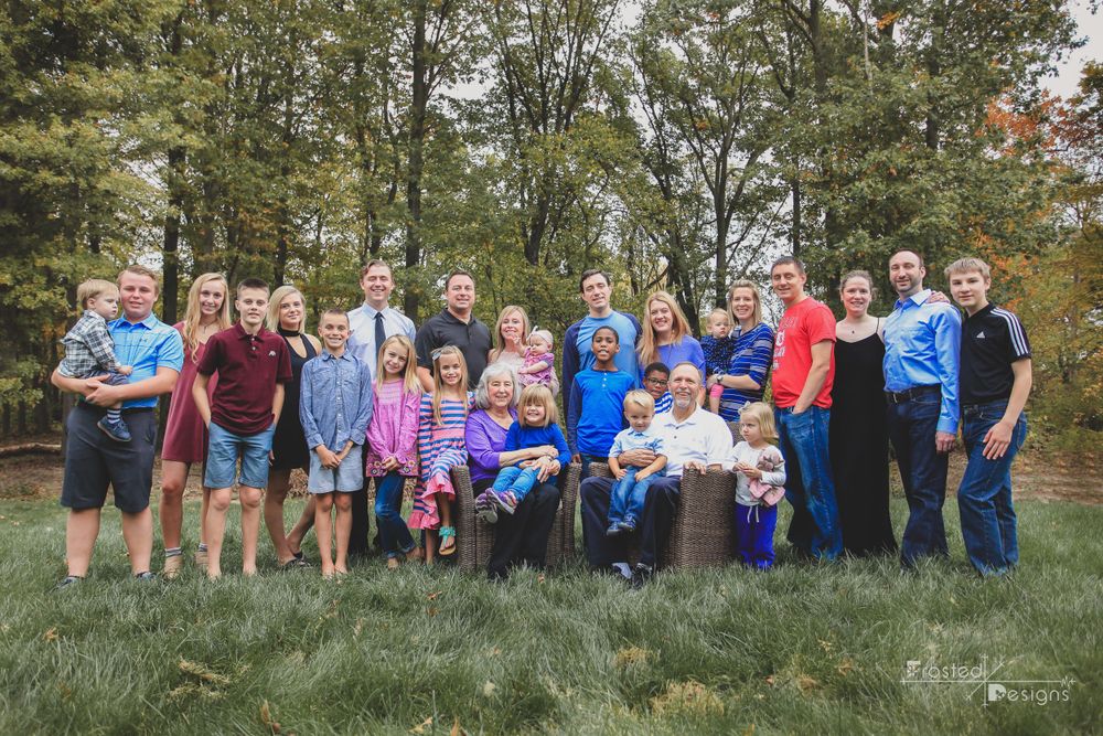 Large extended family with multiple family groups with grandparents seated and their family around them.