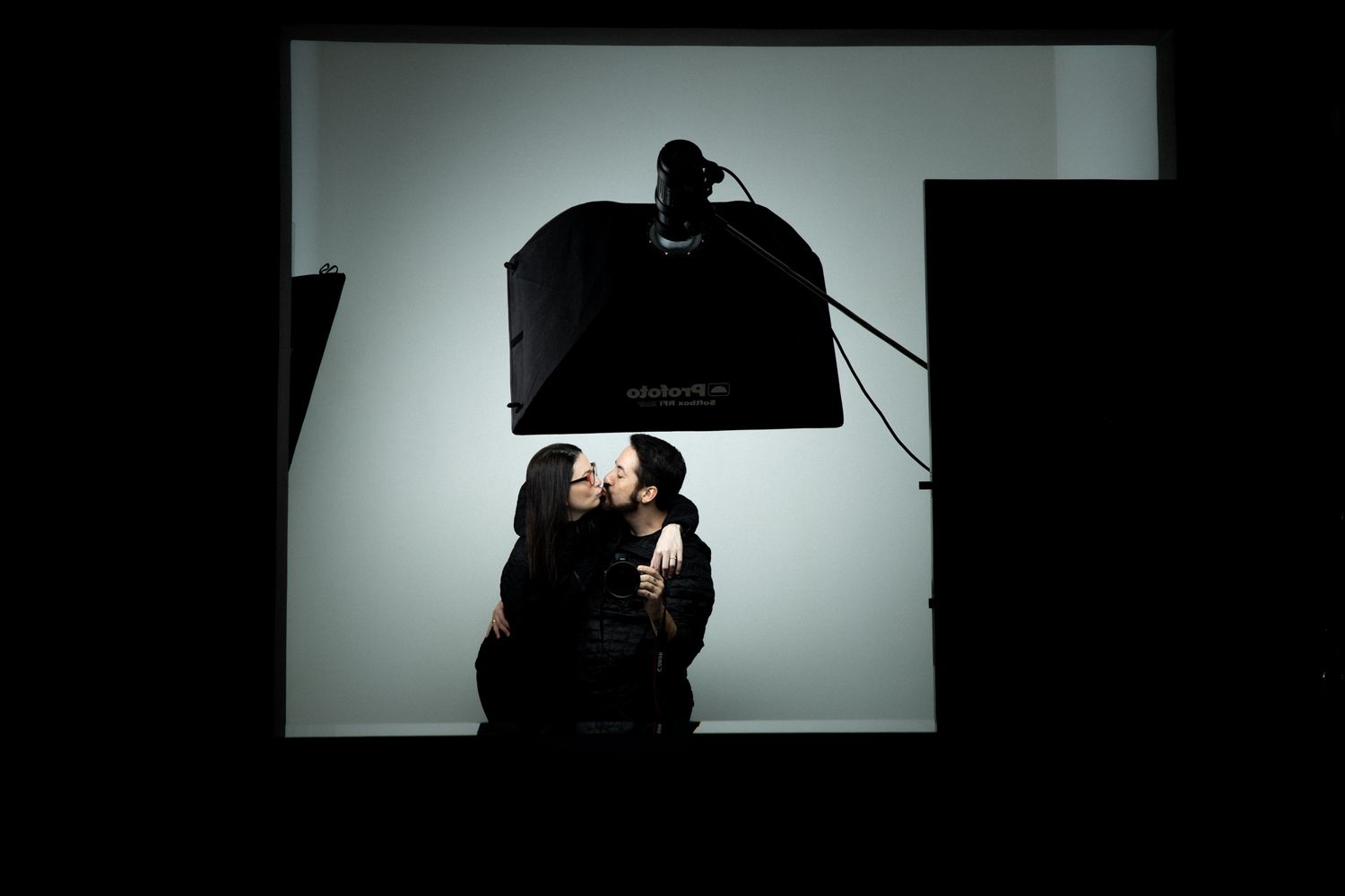 Silhouetted figures embracing under dramatic studio lighting setup.
