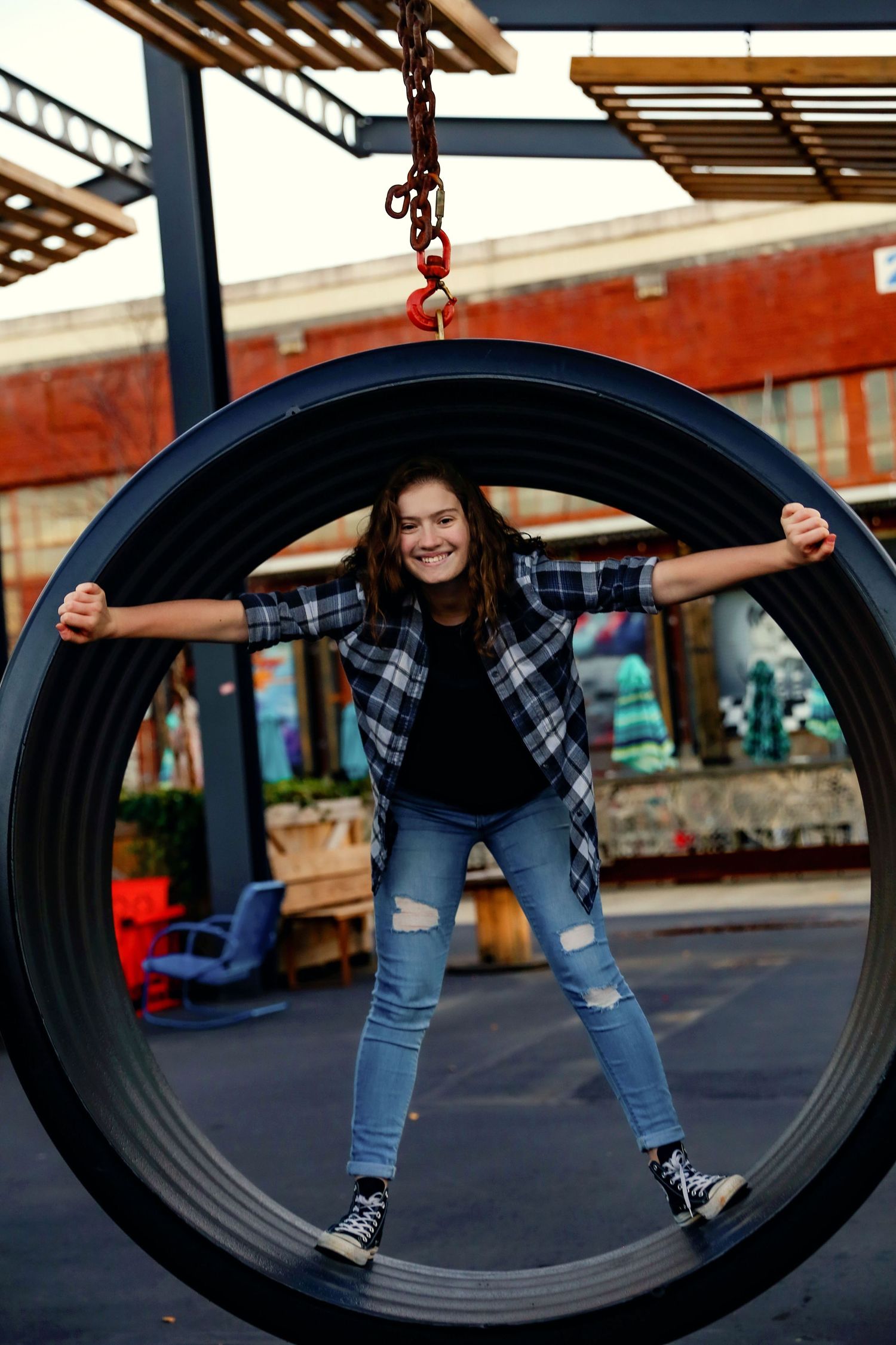 A playful pose inside a large suspended tire ring on a playground.