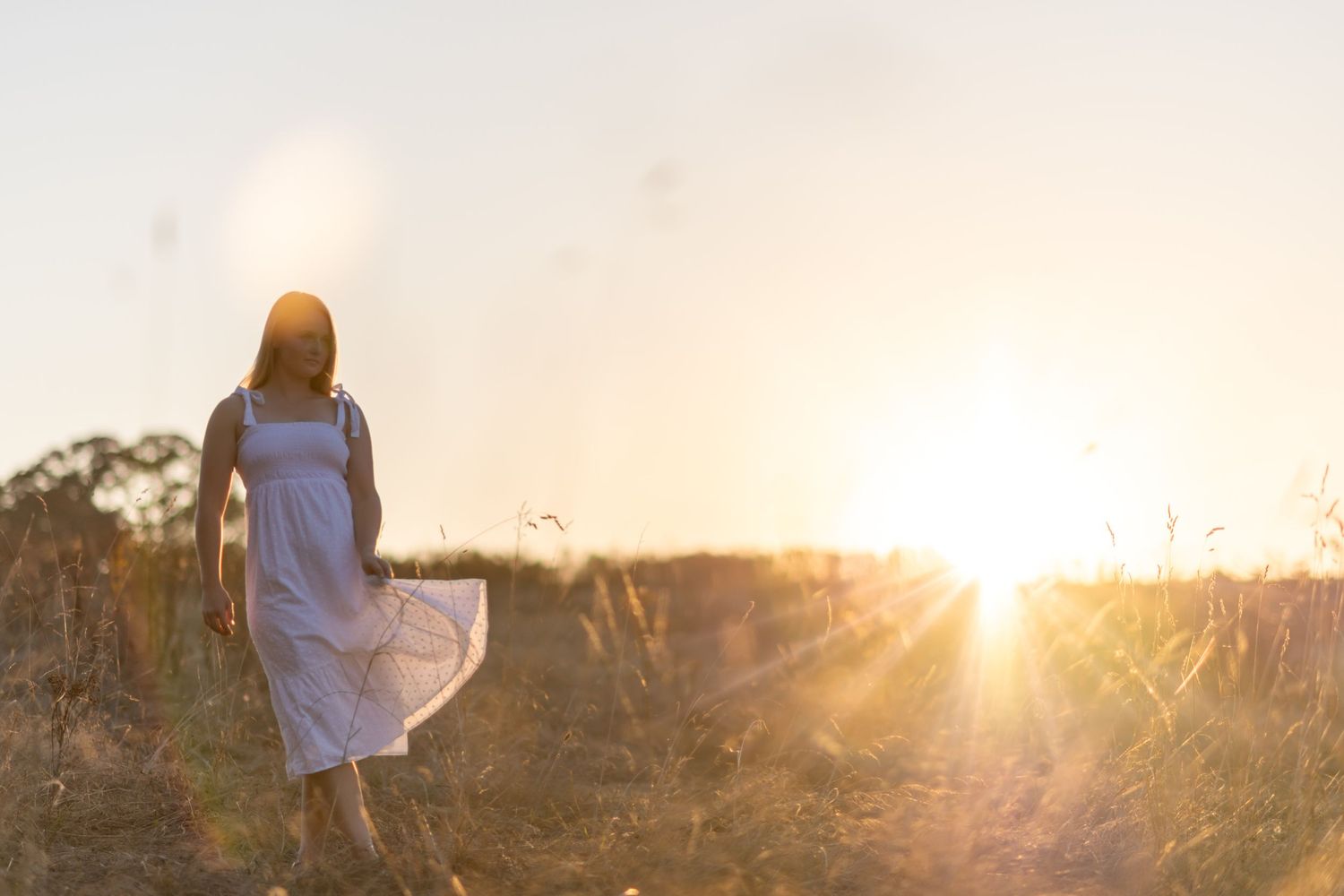 model twirling white sundress in front of setting sun
