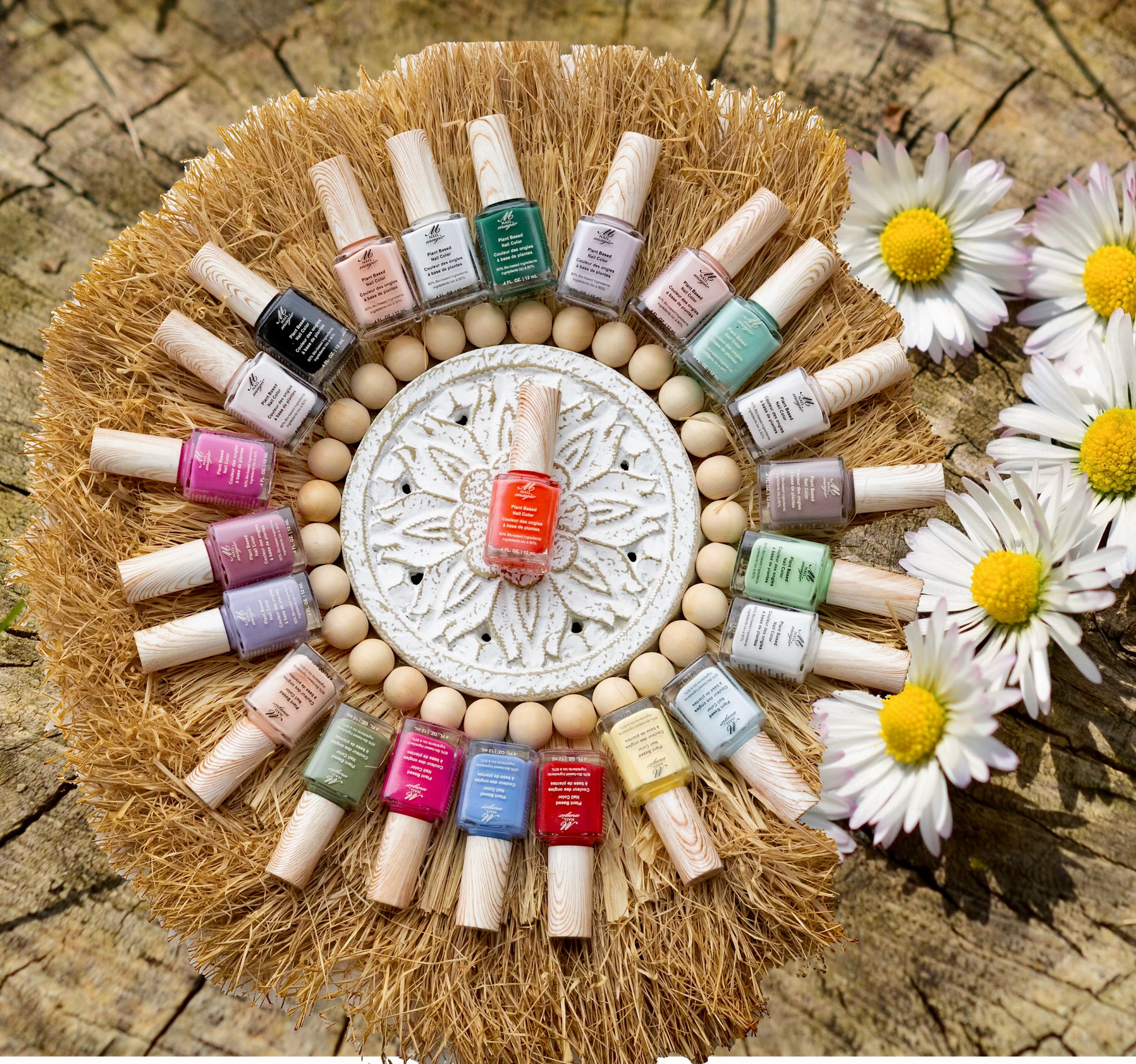 Artistic circular arrangement of colorful nail polishes with daisies on wooden surface.