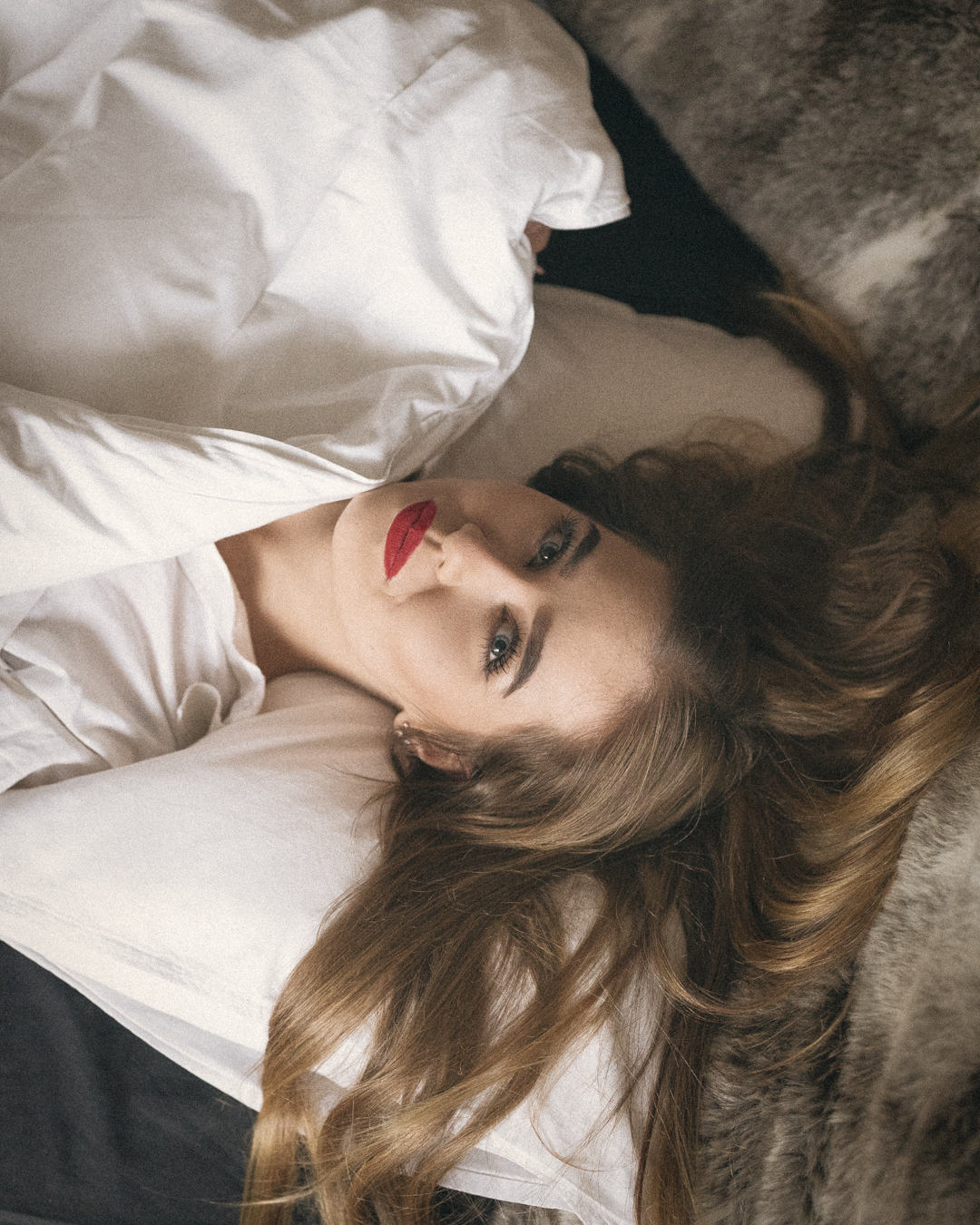 Person in white shirt lying on dark surface with dramatic lighting.