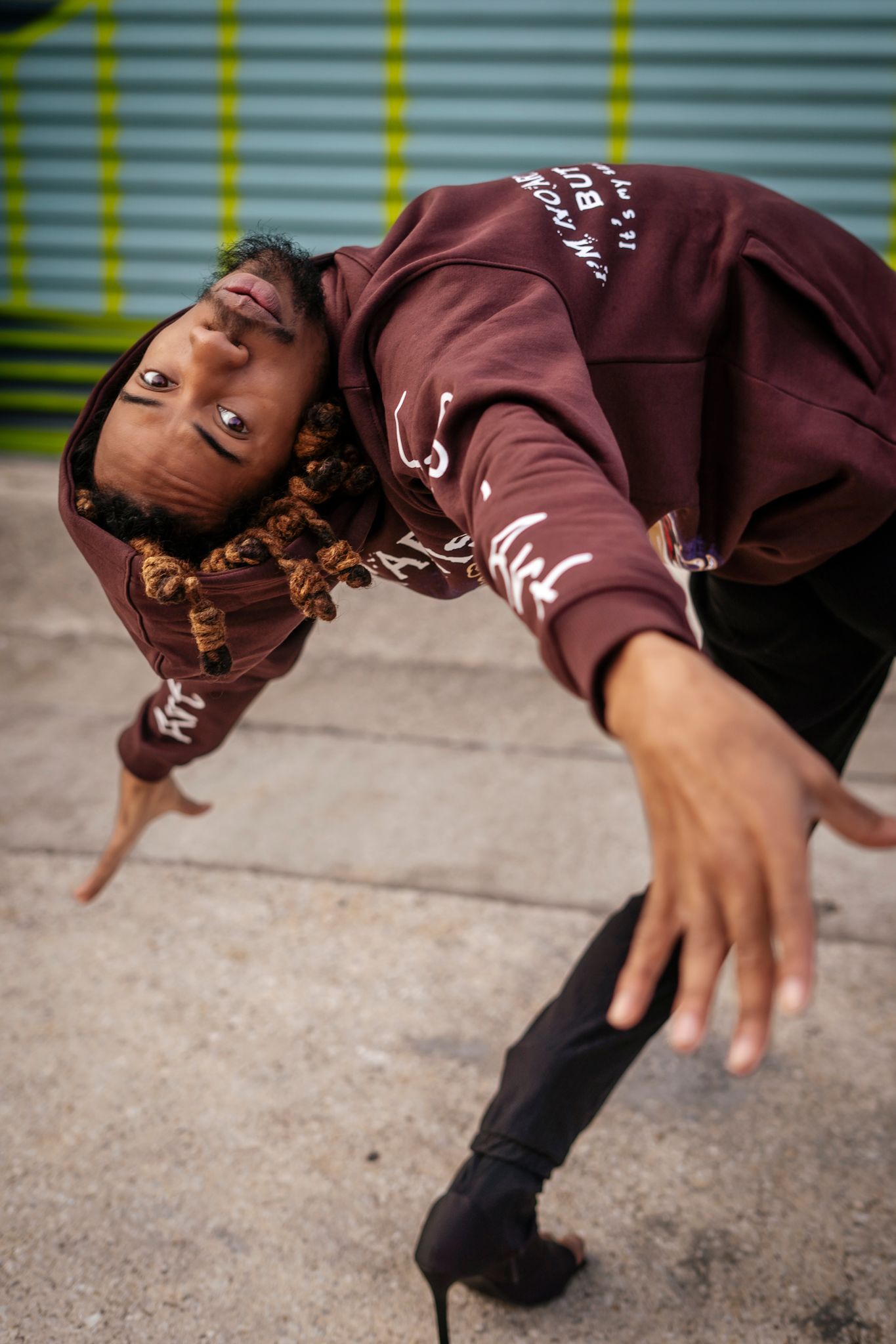 Dynamic shot of dancer in brown hoodie performing street dance move.