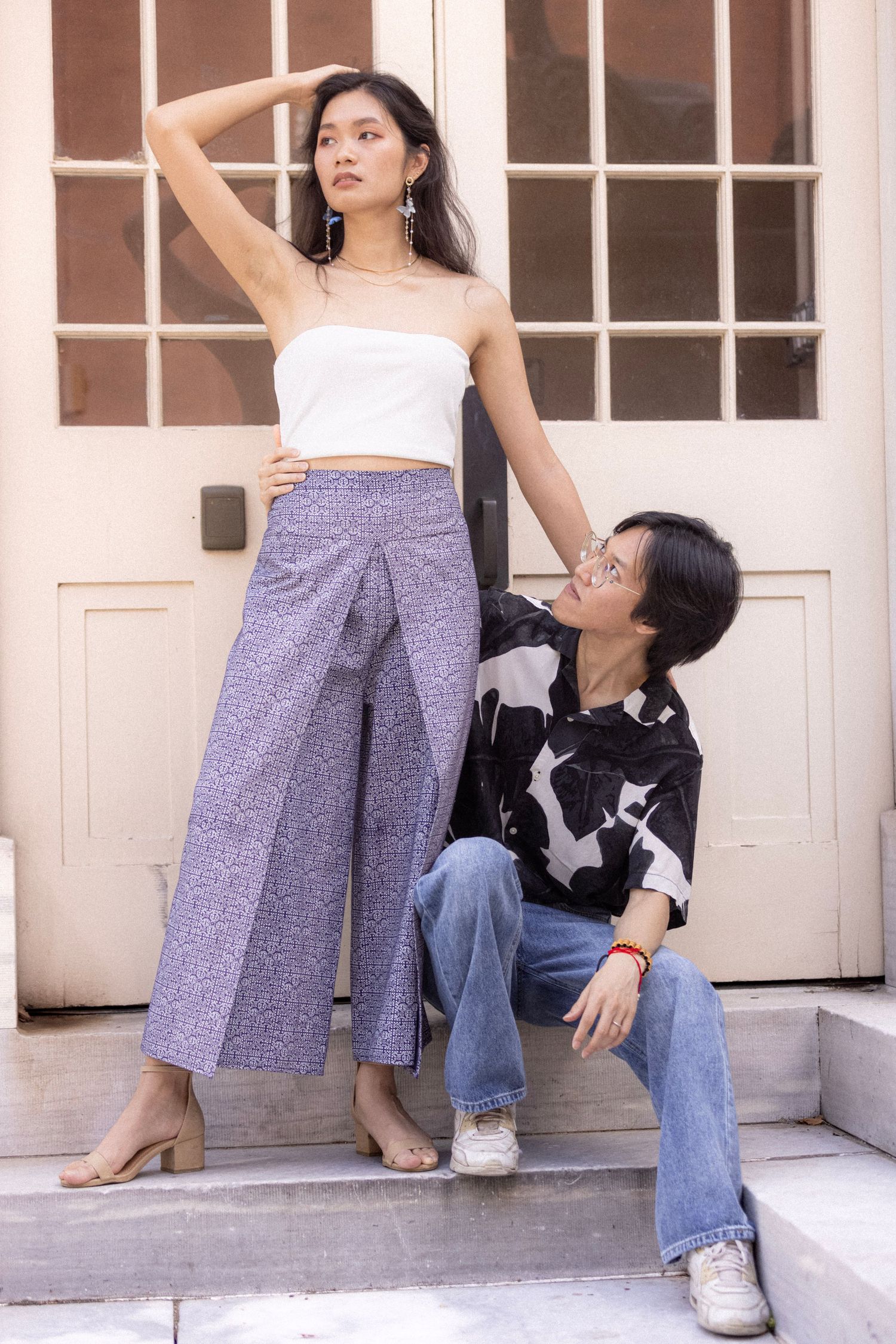 Two people pose on steps wearing contrasting outfits in casual and artistic composition.