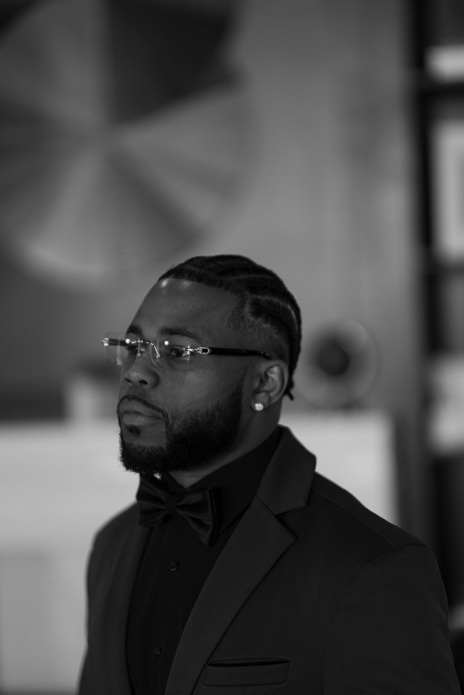Professional portrait in black and white of a man wearing glasses and formal attire.
