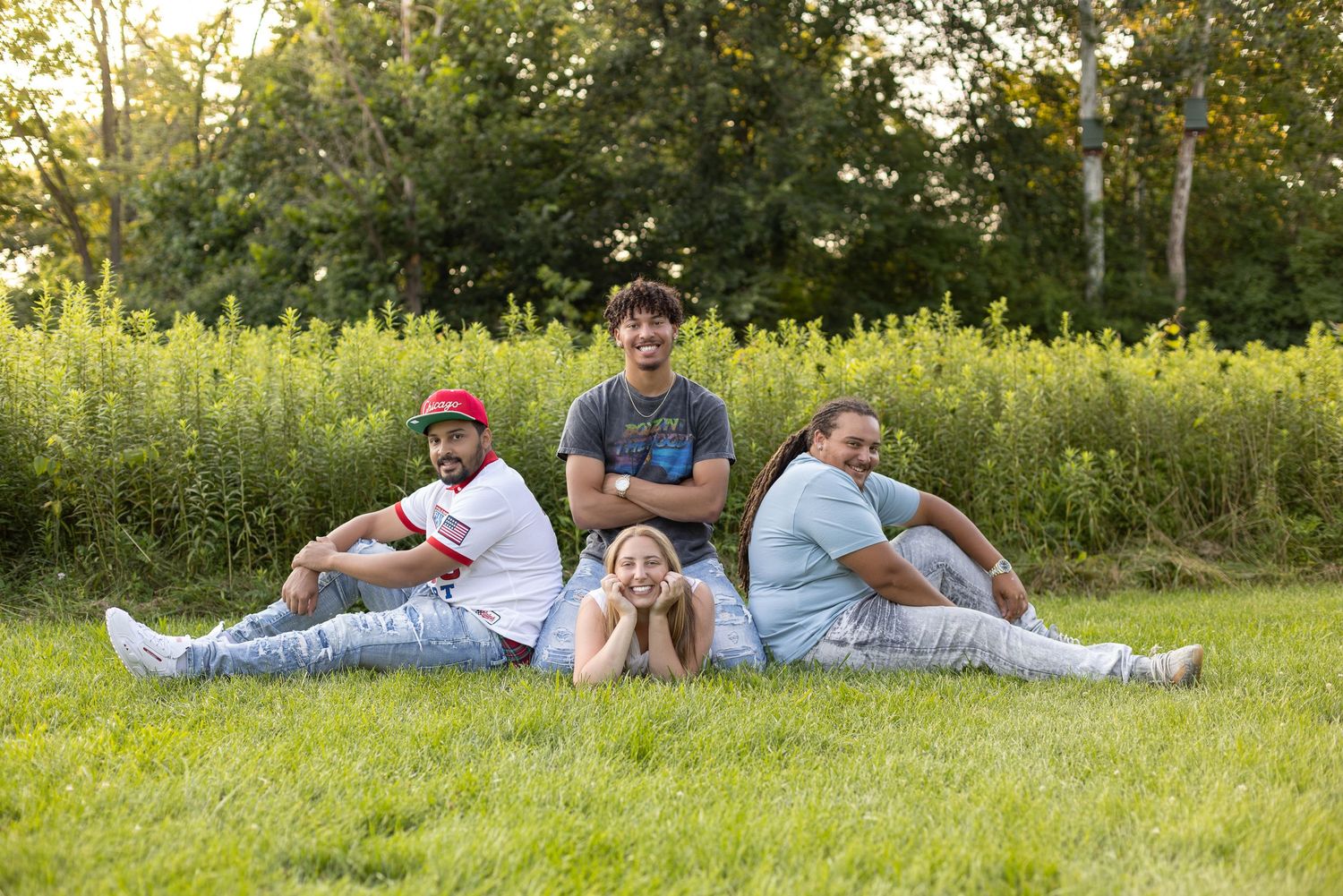 Group lounging together on grass during outdoor photo session.