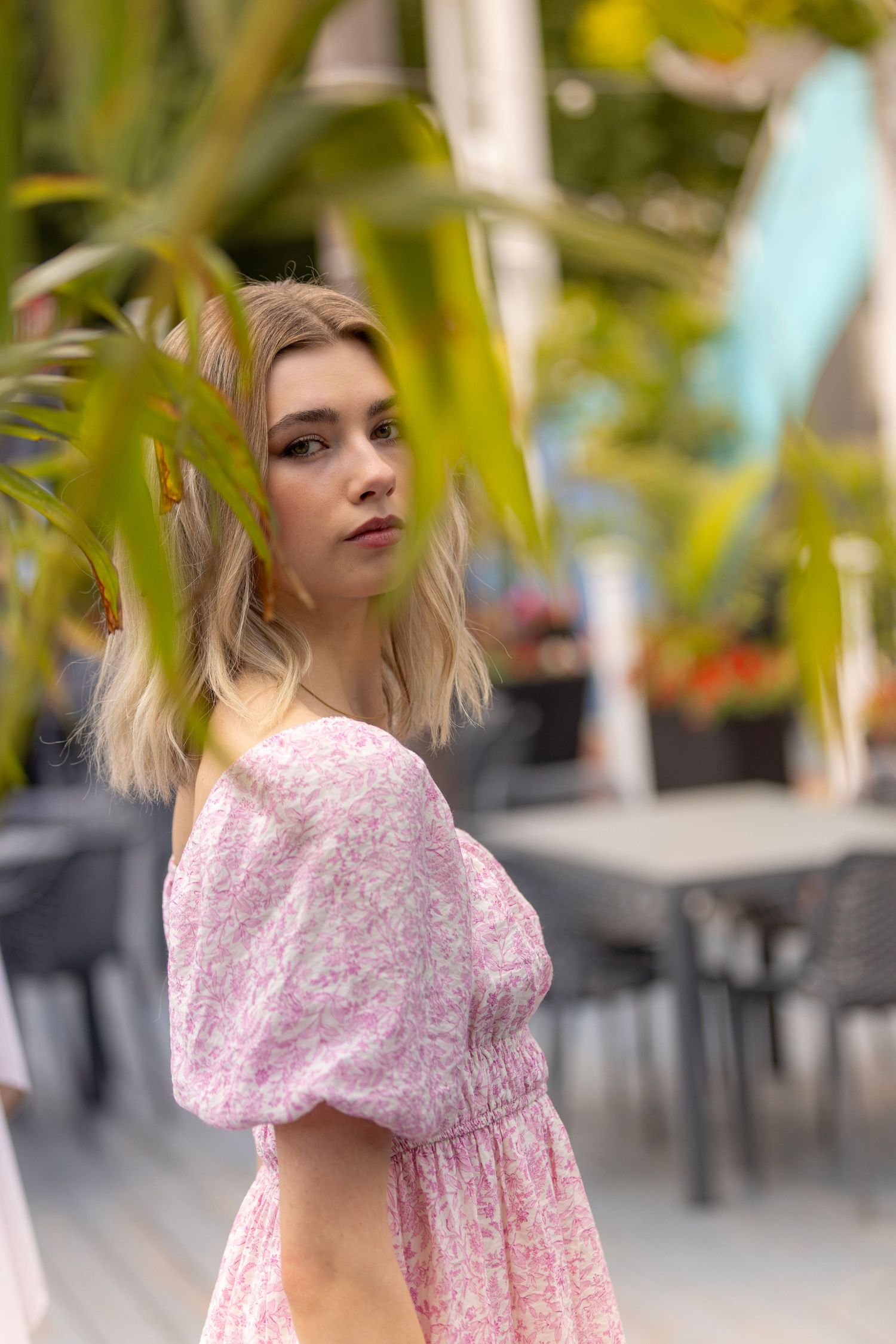 Dreamy outdoor portrait in pink floral dress with soft focus foliage.