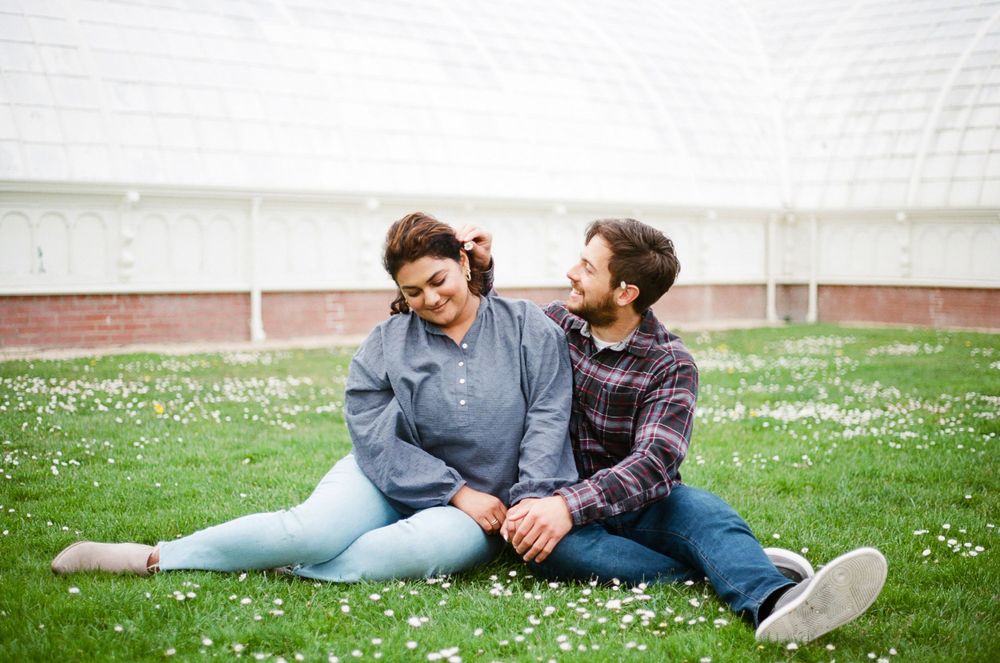35mm film portrait of beautiful couple sitting in the grass at the park