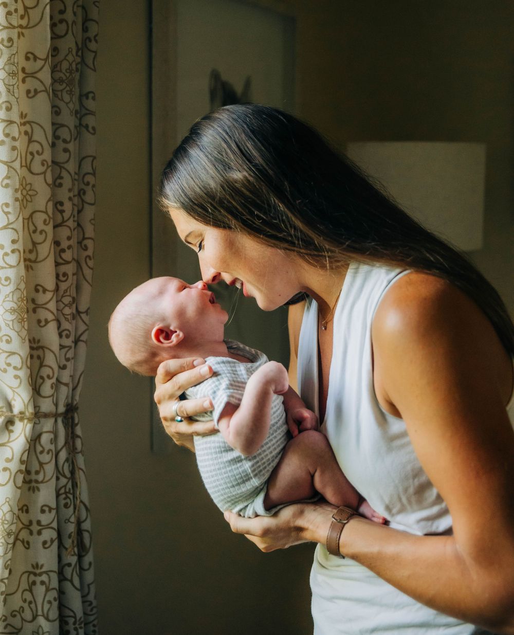 A mom kissing her newborn baby by Traverse City family photographer Grace Hudson
