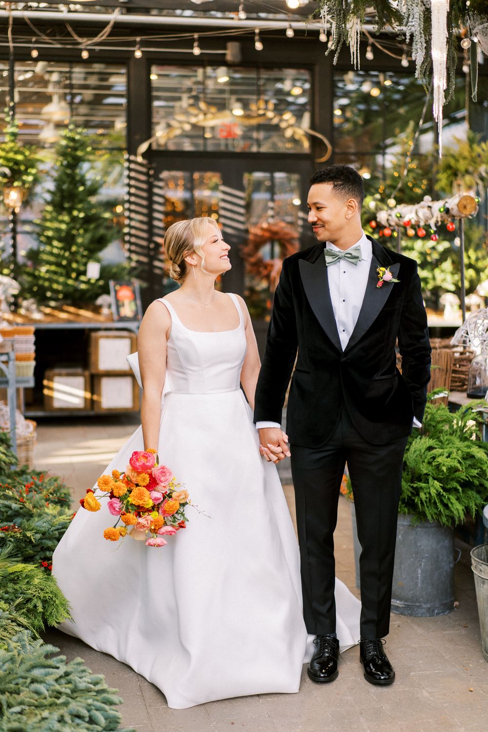 Garden wedding portrait with lush greenery and orange floral bouquet.
