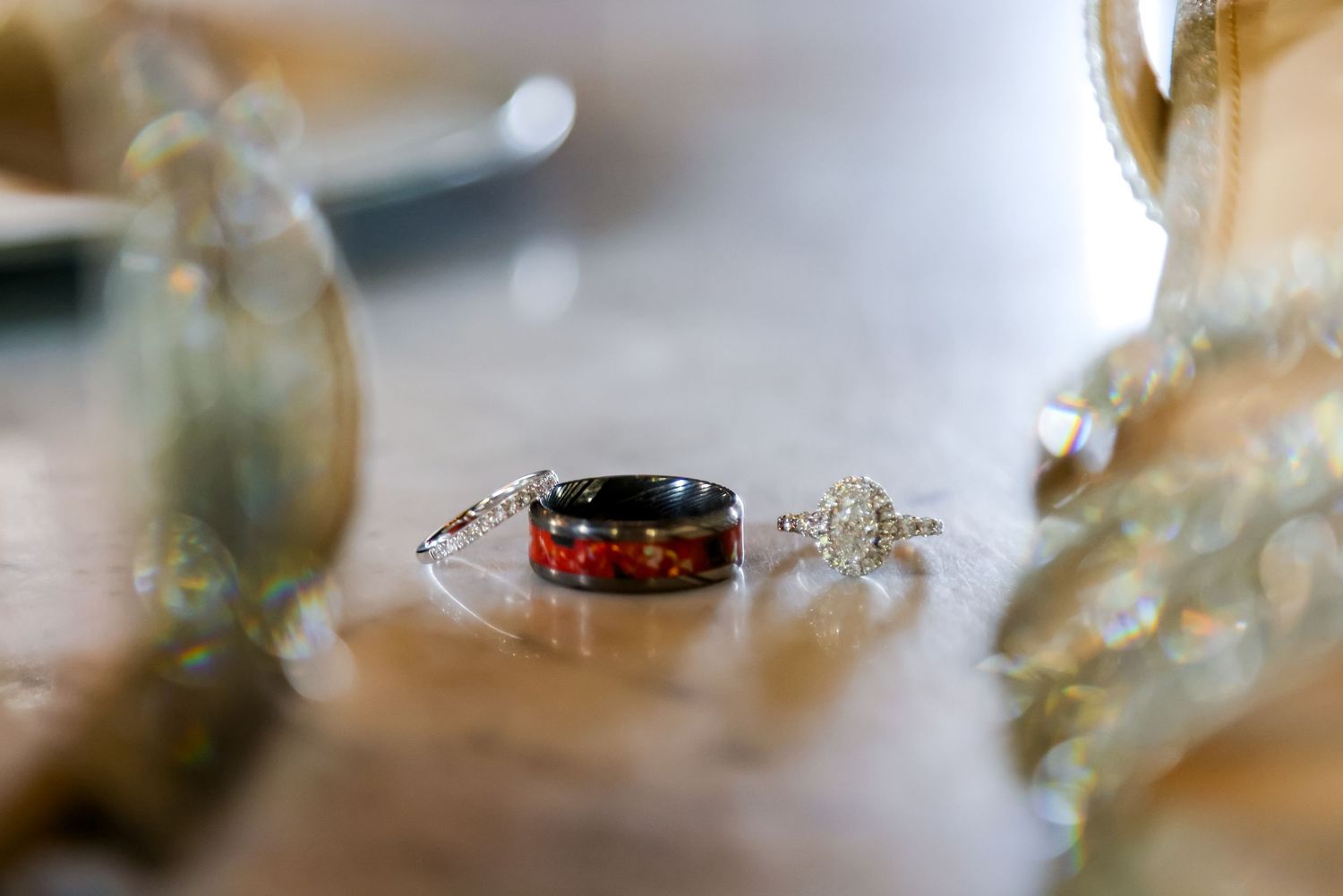 Close-up of wedding rings with unique black and gold design on reflective surface.