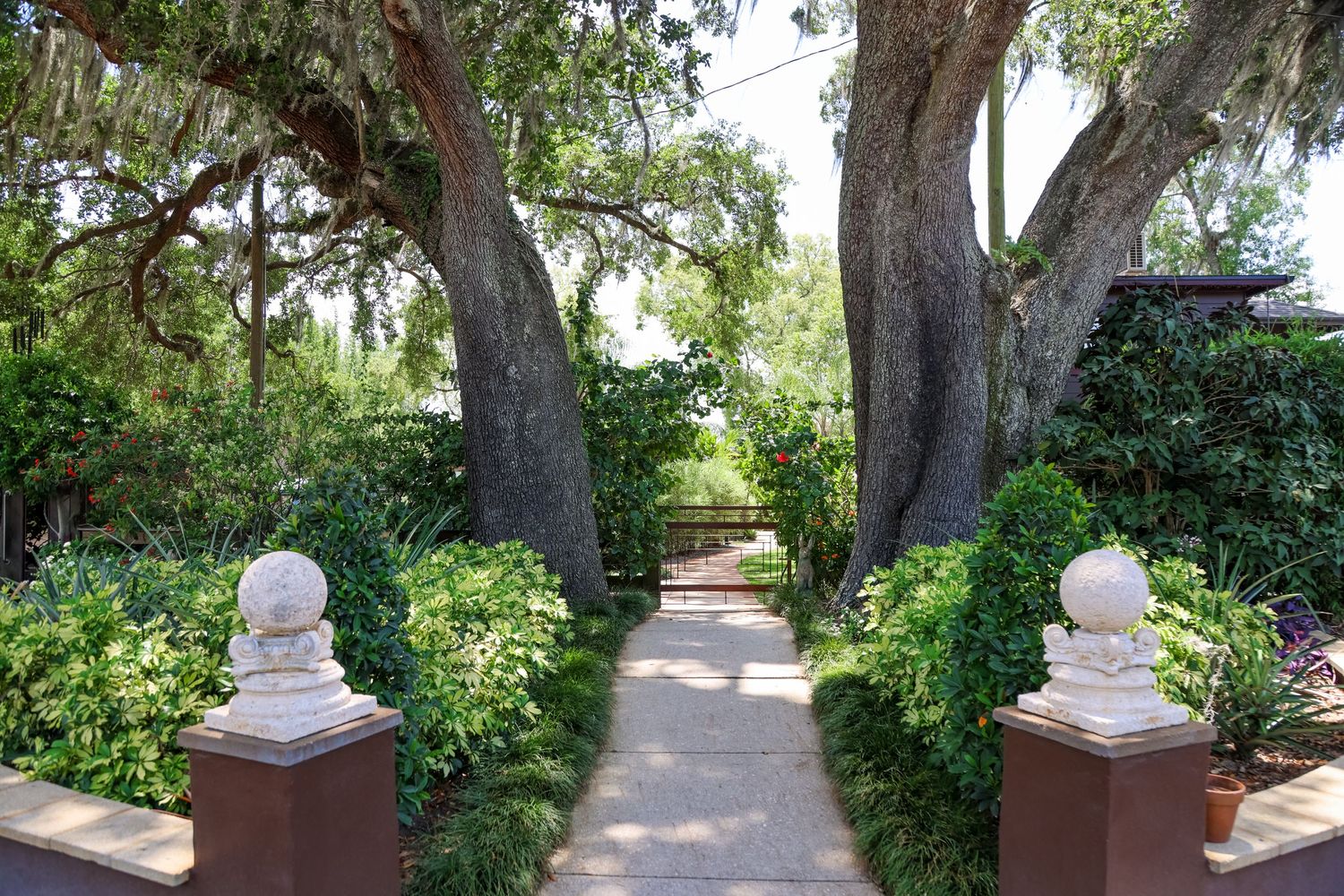 Stone pillar lined garden pathway with overhanging trees creating a romantic wedding venue entrance.