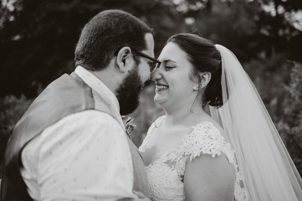 Close-up black and white photo of a joyful wedding couple sharing an intimate moment.