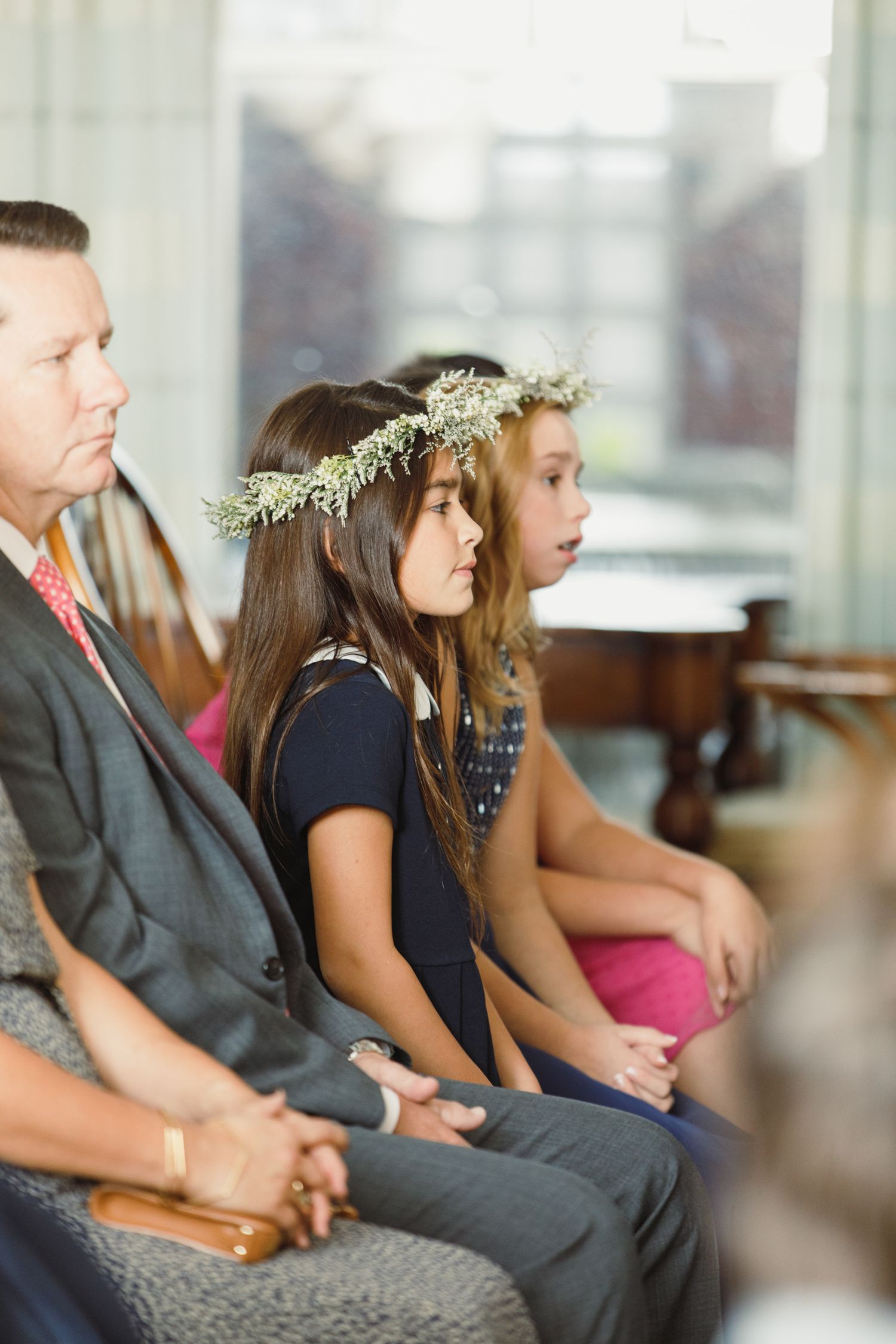 Young attendees in formal wear sit together during a wedding ceremony.