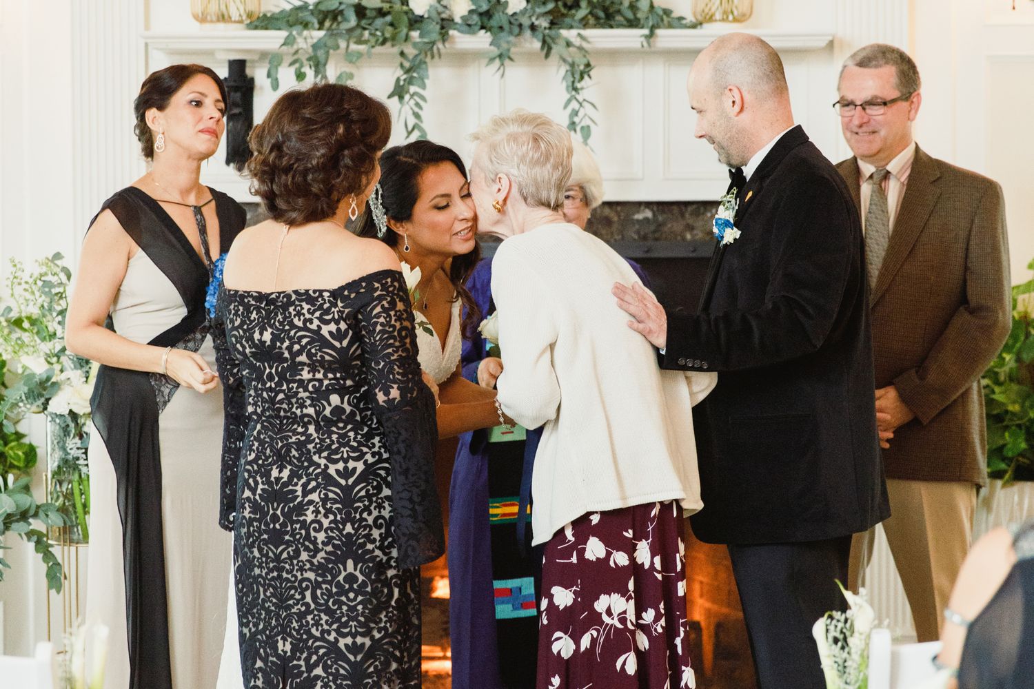 Wedding party members interact during a ceremony in a beautifully decorated indoor venue.