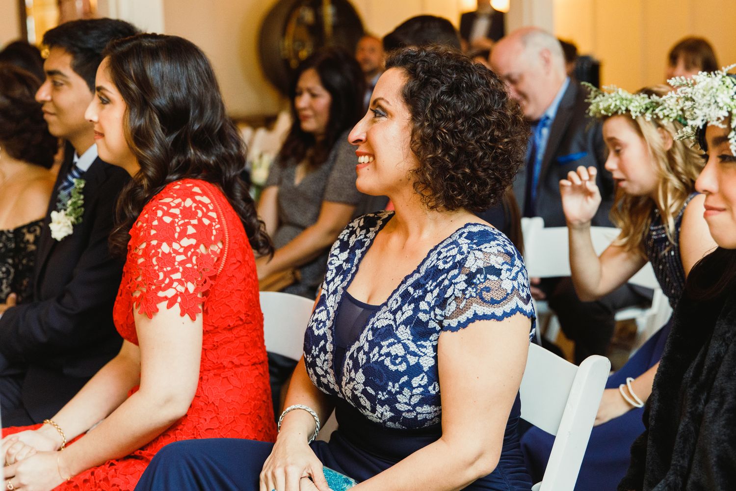 Wedding guests in colorful formal attire seated during ceremony.