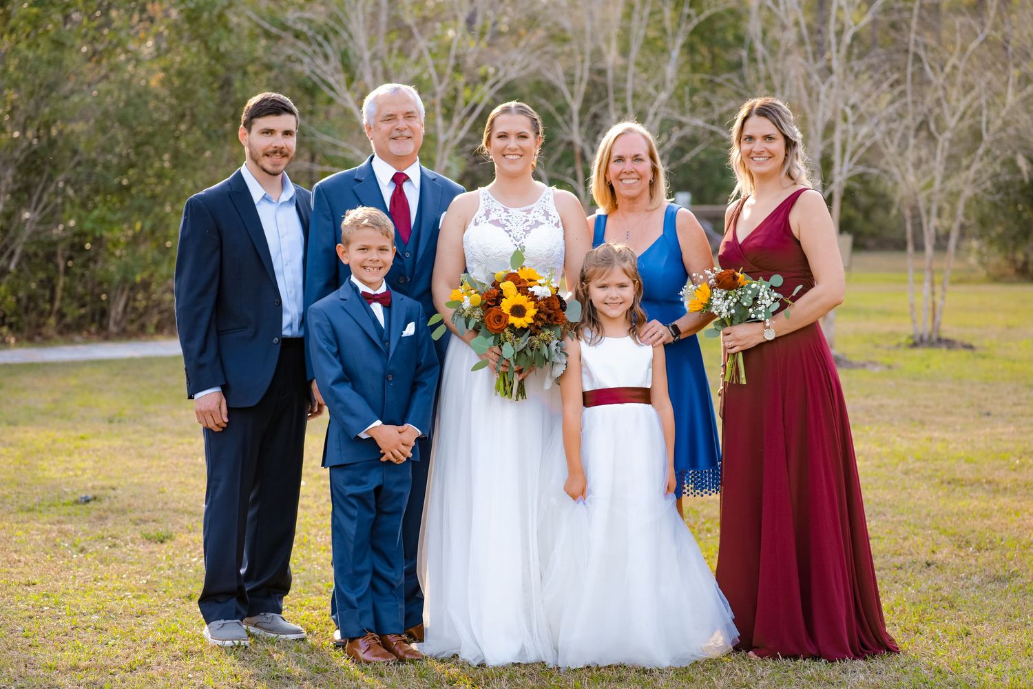 Wedding party group photo with bridal party in navy and burgundy attire with sunflower bouquets.