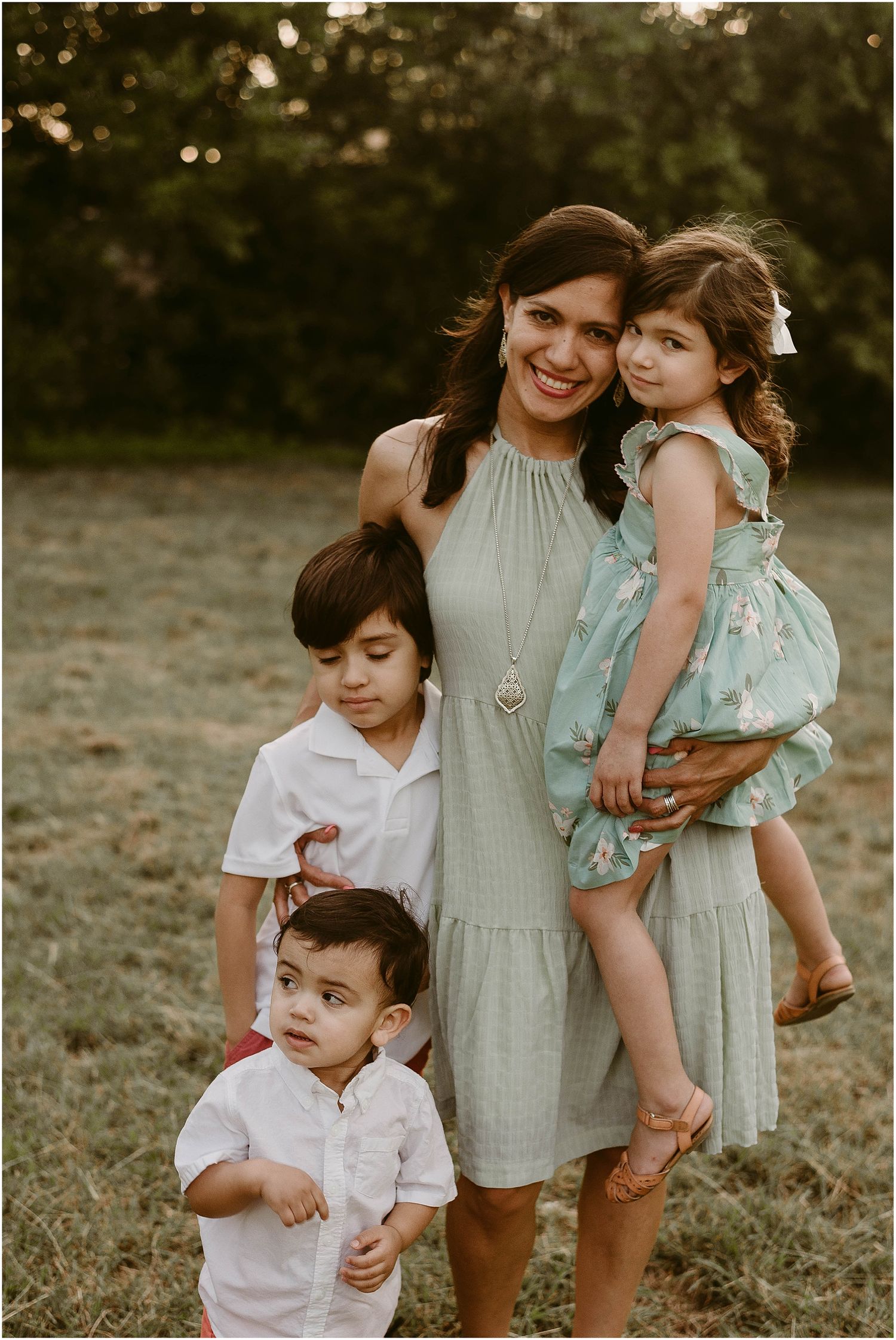 A heartwarming family portrait showing three children and their parent in a natural outdoor setting.