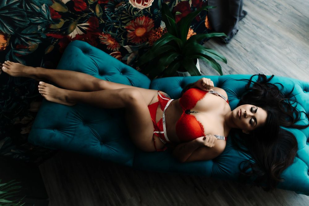 sexy boudoir woman in red lingerie laying on chaise