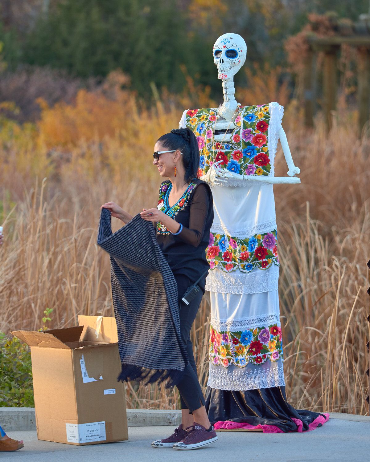 Ludevina dresses the skeletal Catrina in layers of white cloth with colorful fabric flowers stitched in patterns.