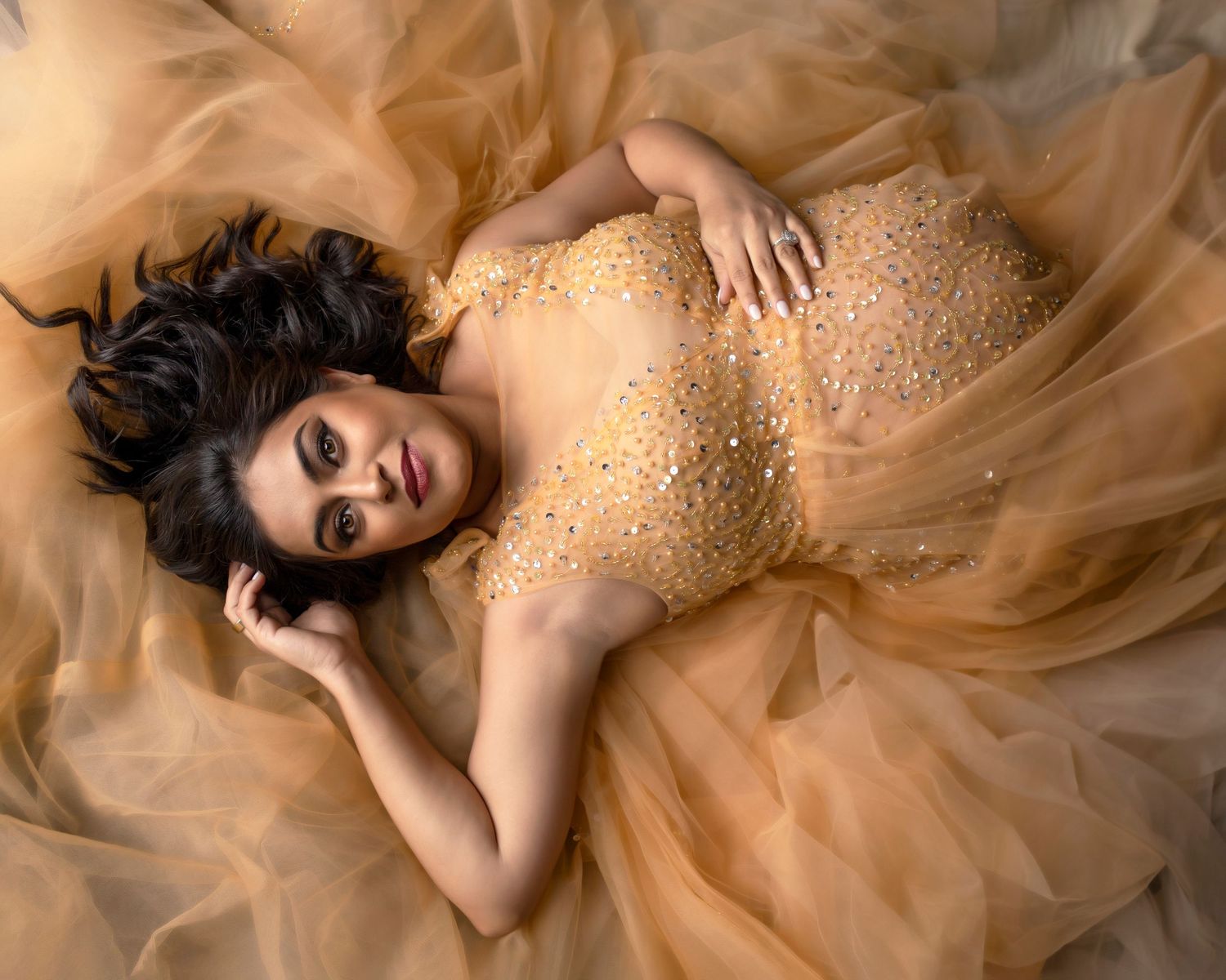 beautiful mother in gold dress holding baby bump.