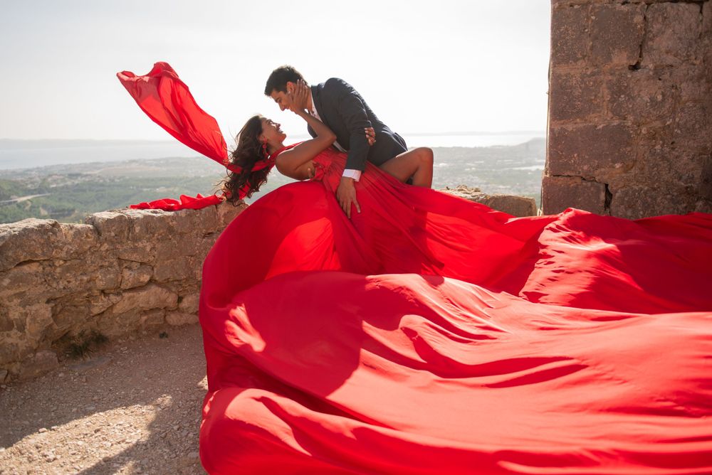 A dramatic scene with flowing red fabric against a stone wall backdrop.