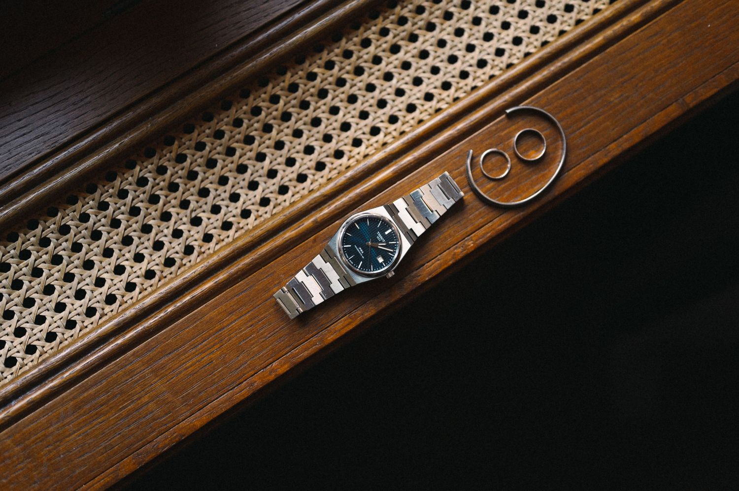 Vintage silver watch placed on wooden surface with decorative pattern.