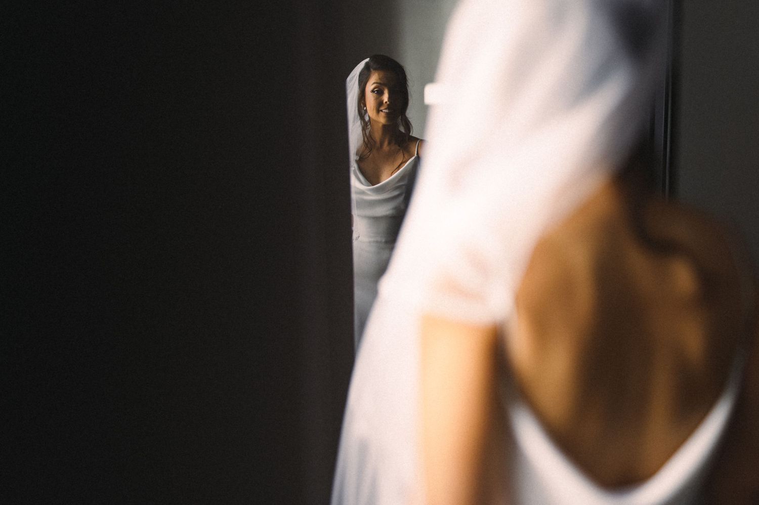 Stylish wedding preparation scene with dramatic lighting and reflections in a mirror.