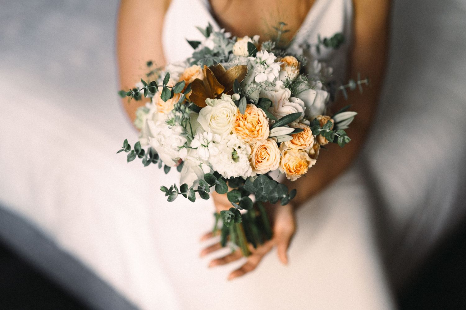 Close-up of bridal bouquet with peach roses, white flowers and eucalyptus.