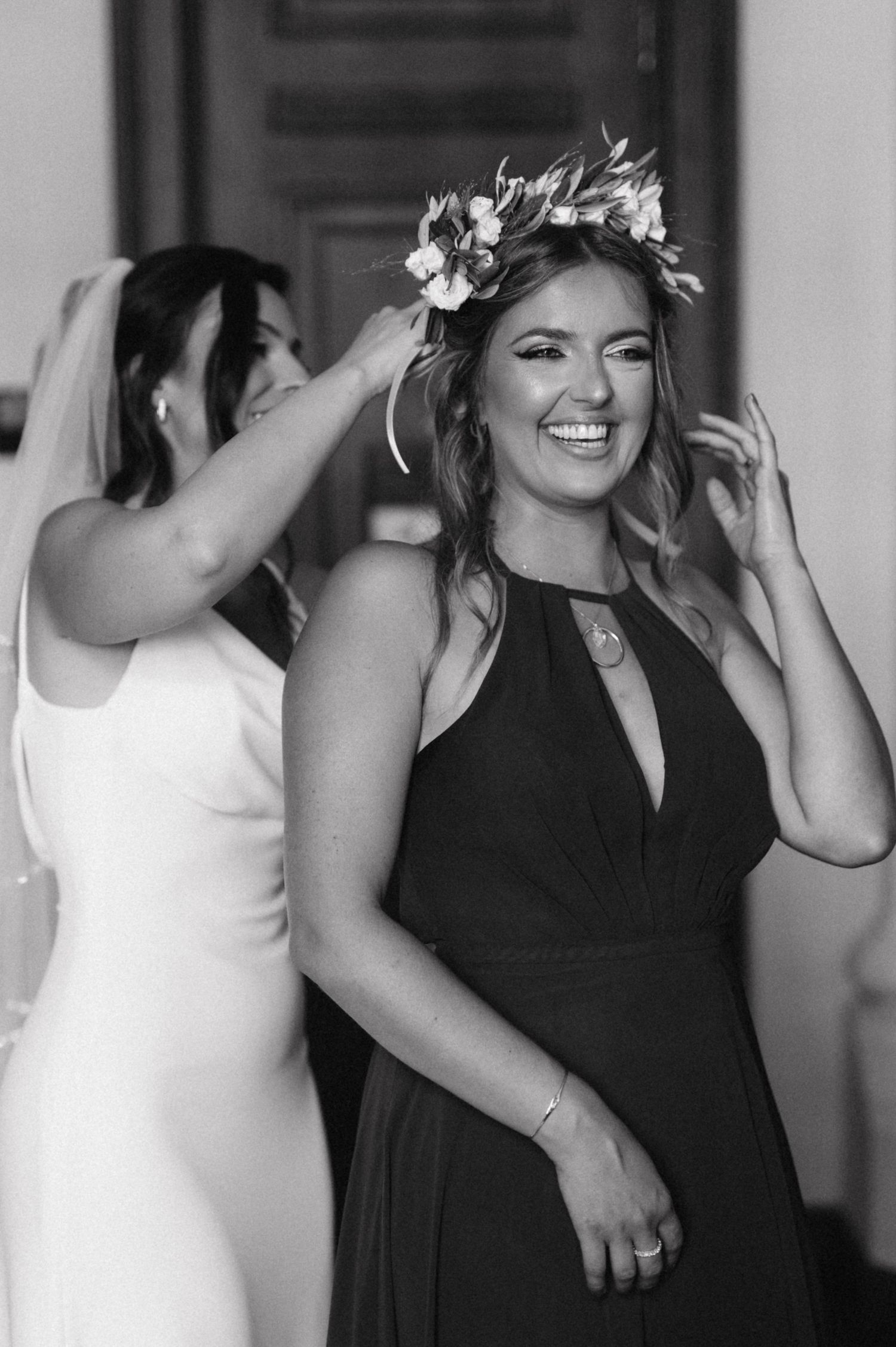 Joyful wedding preparation moment with floral crown adjustments.