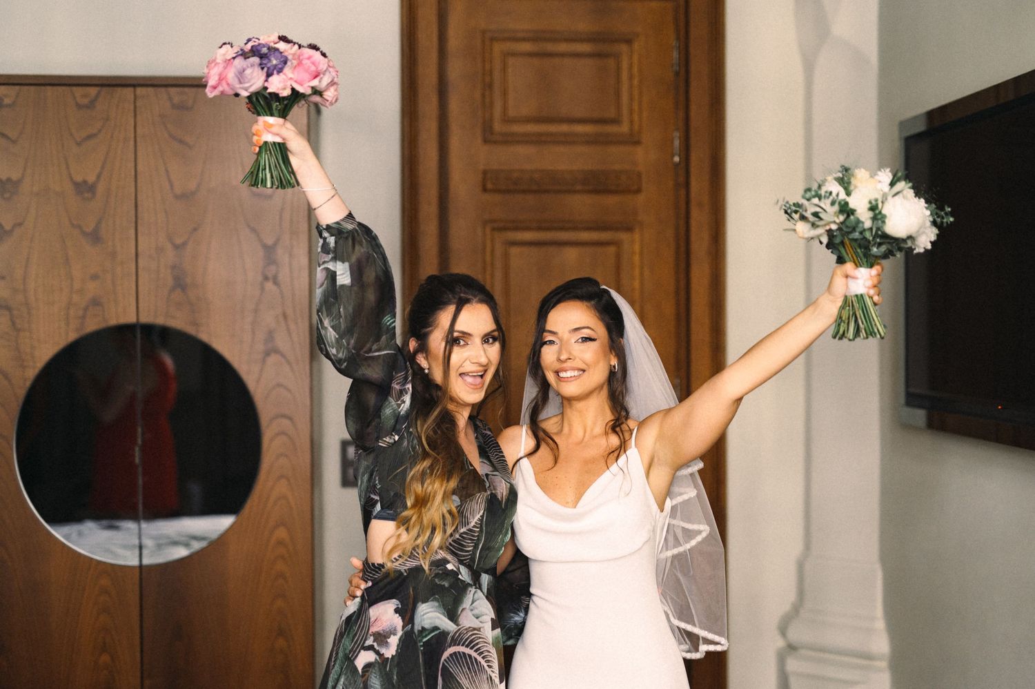 Celebratory wedding moment with raised bouquets and joyful expressions.