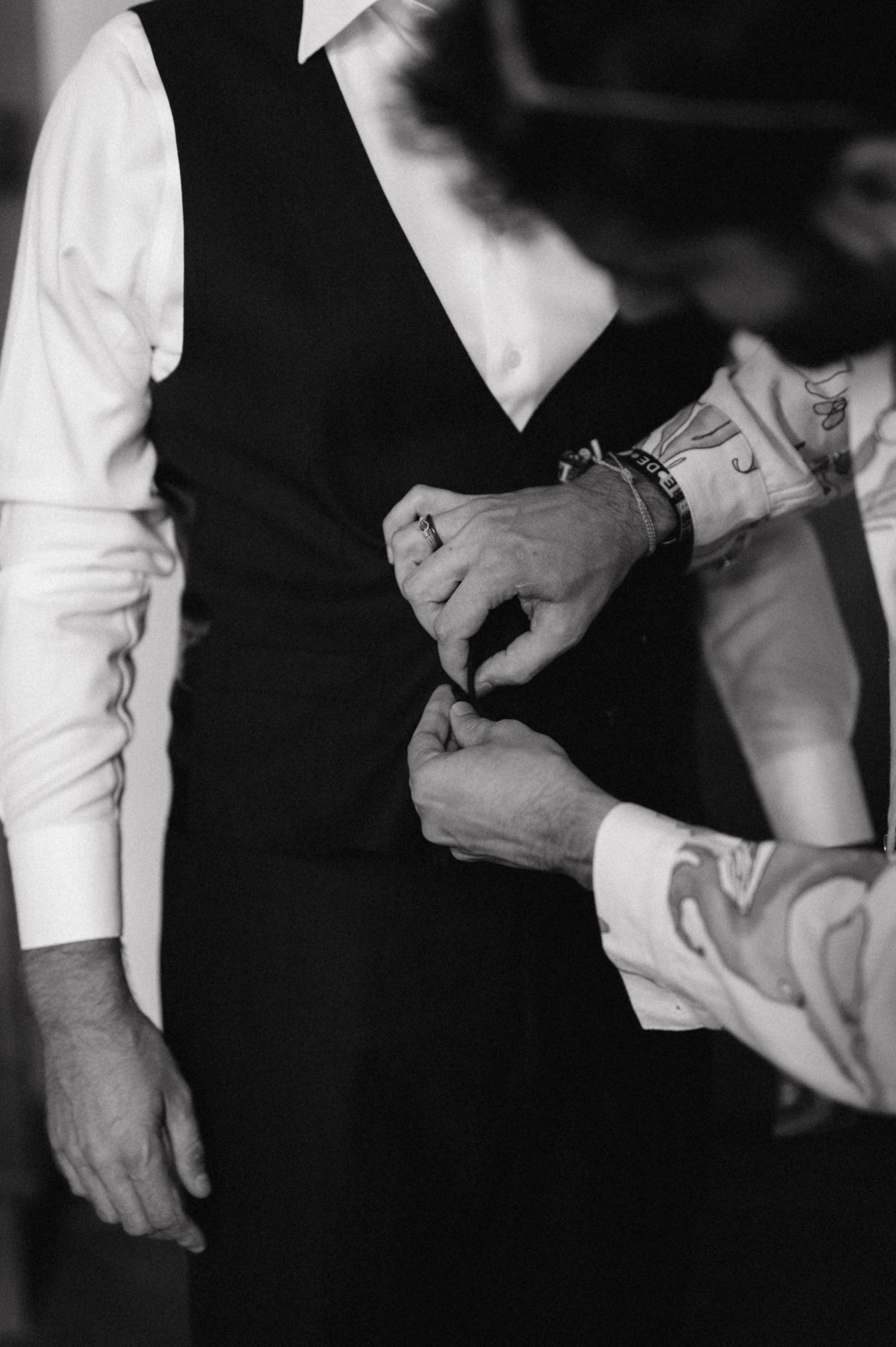 Black and white detail shot of wedding attire adjustments.