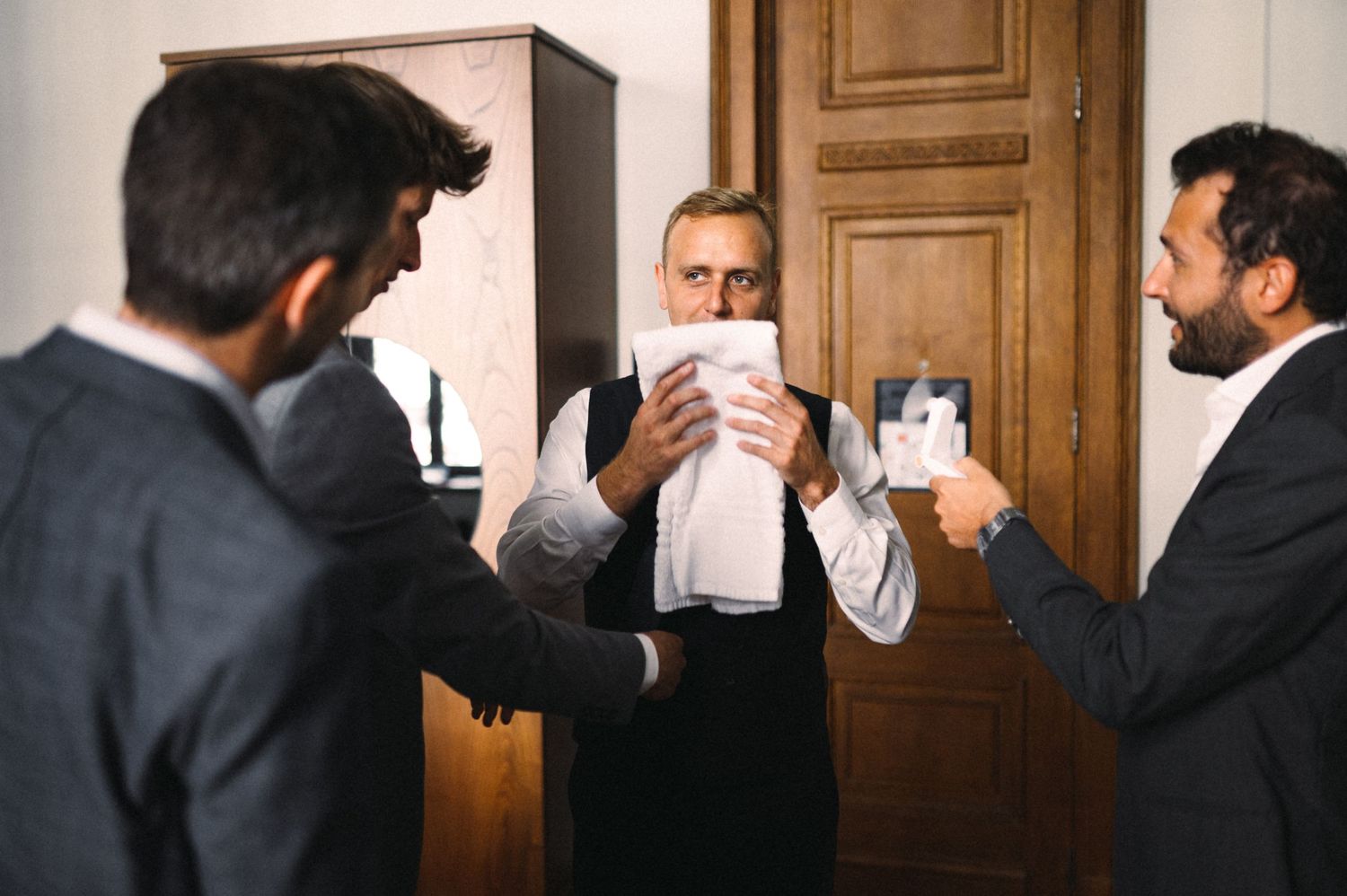 A group of well-dressed men sharing drinks and conversing in an indoor setting.
