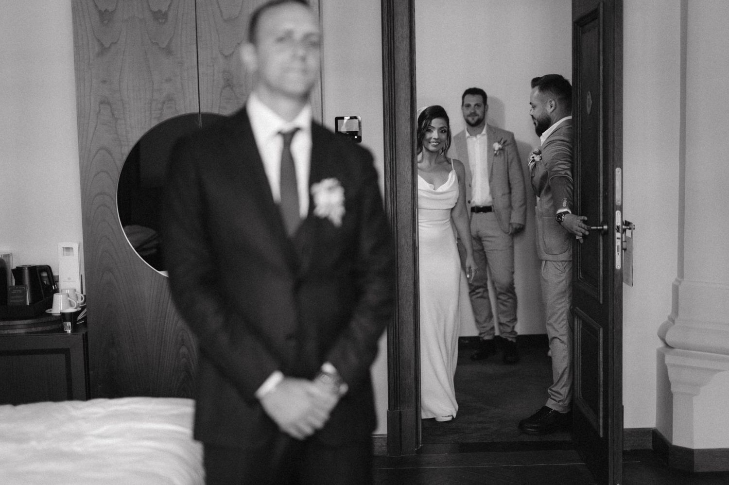 Wedding first look moment captured in black and white through doorway.