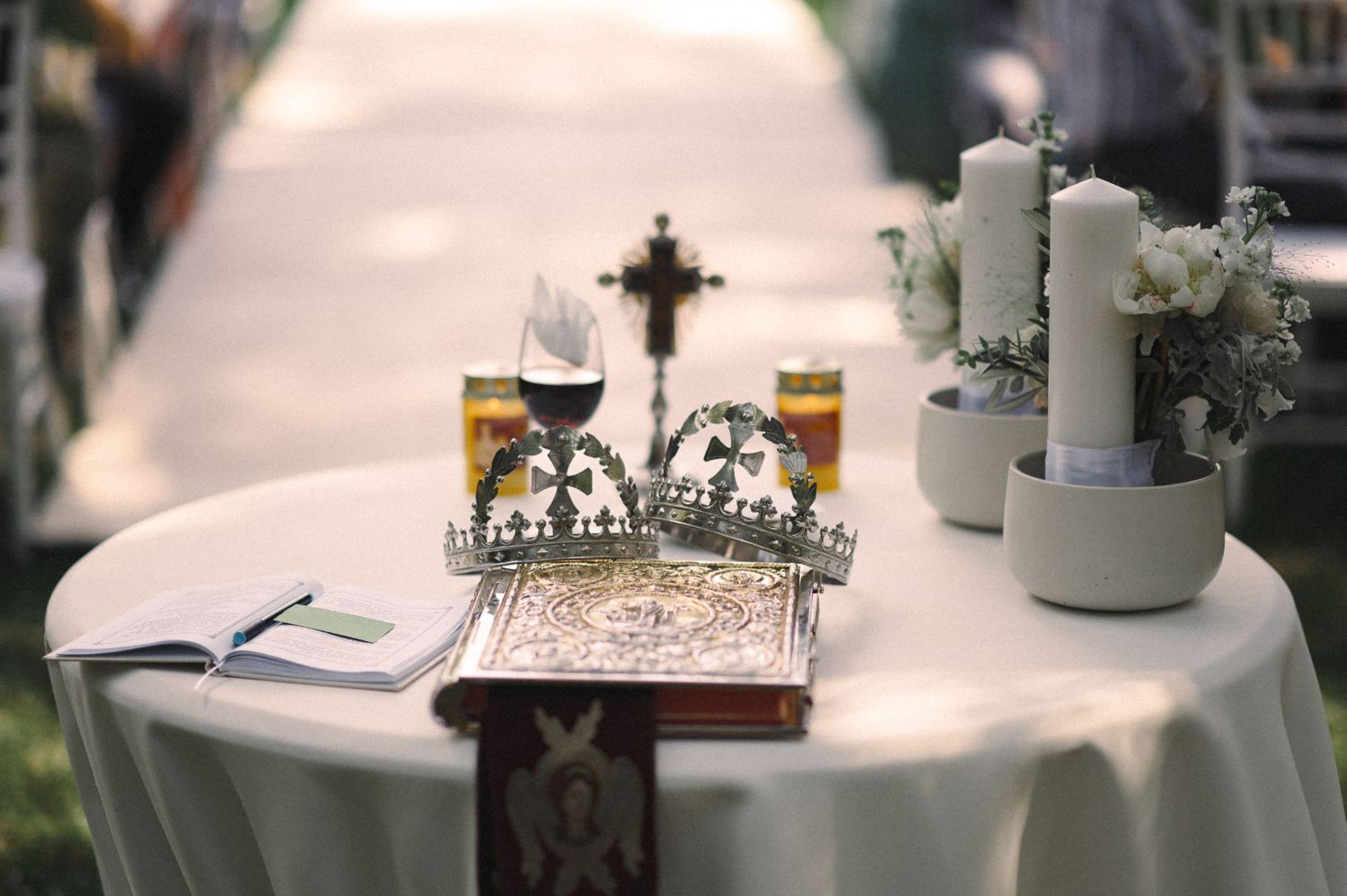 Wedding ceremony table with white candles, decorative cross, and delicate tabletop details.