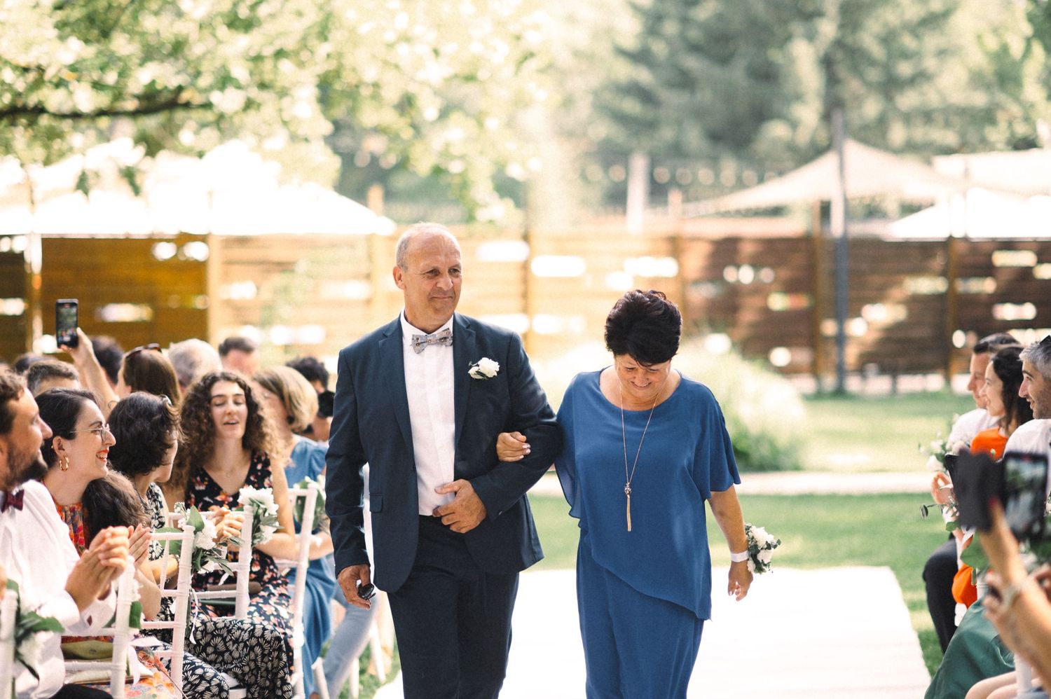 Wedding processional walking down the outdoor aisle with seated guests.